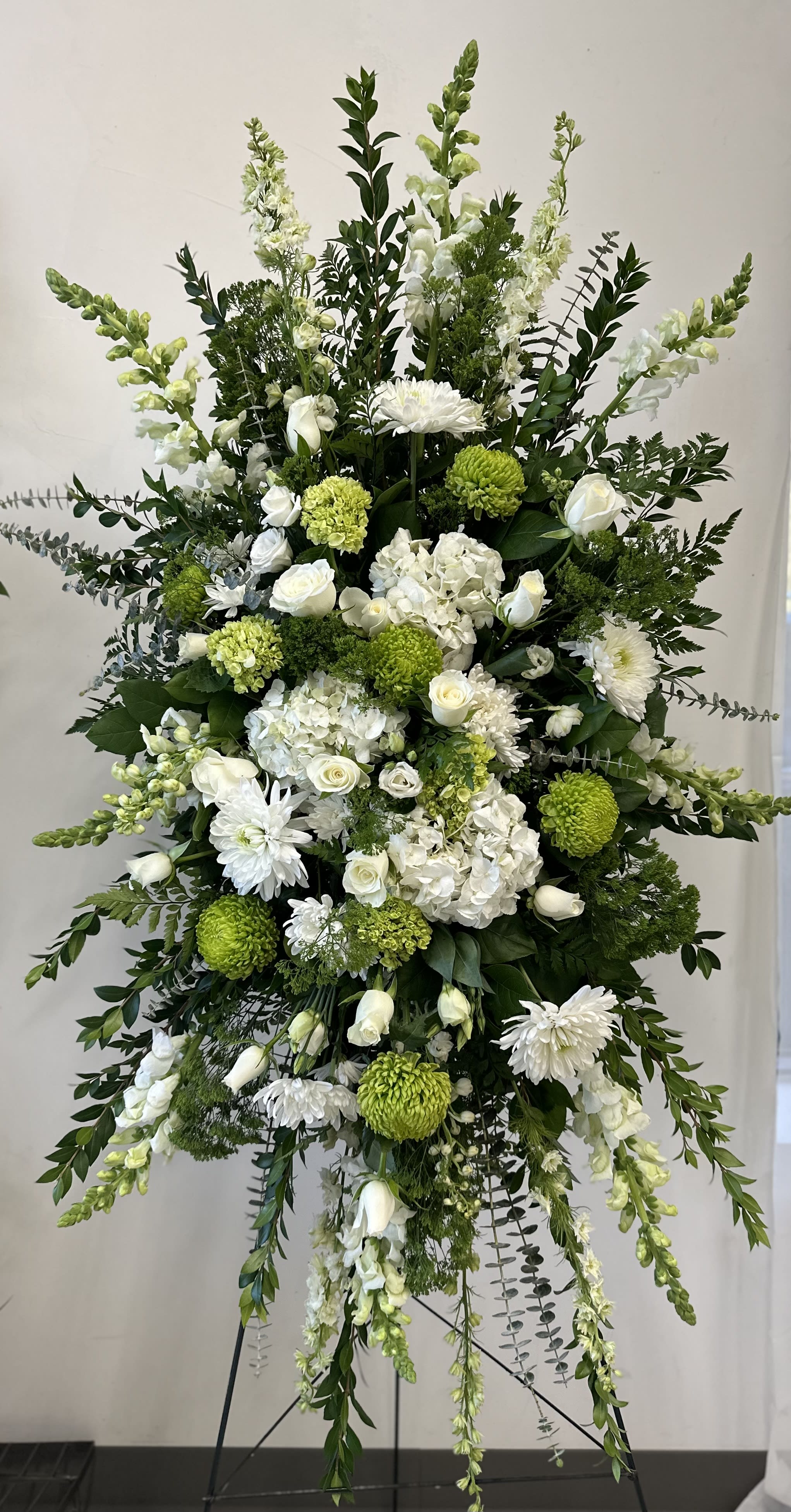 Tall white and green funeral spray on a stand