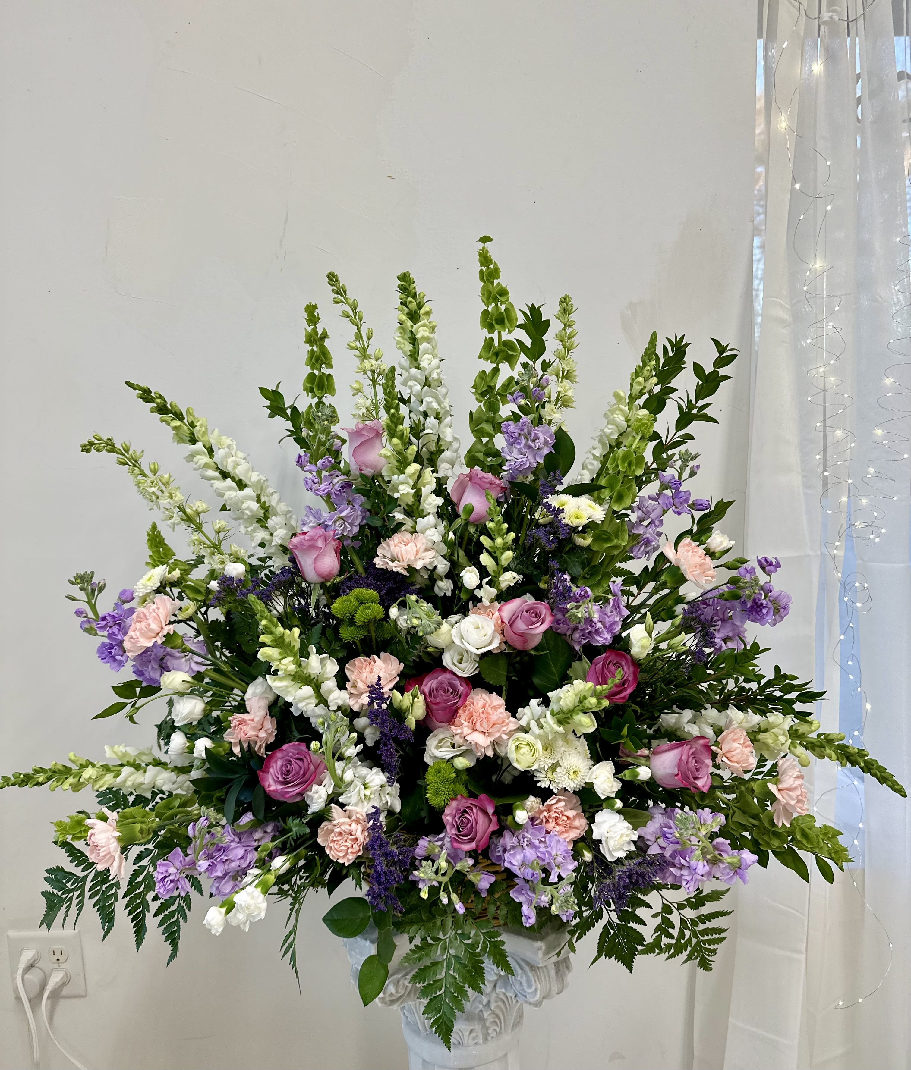 Large pastel floral arrangement in a white pedestal vase