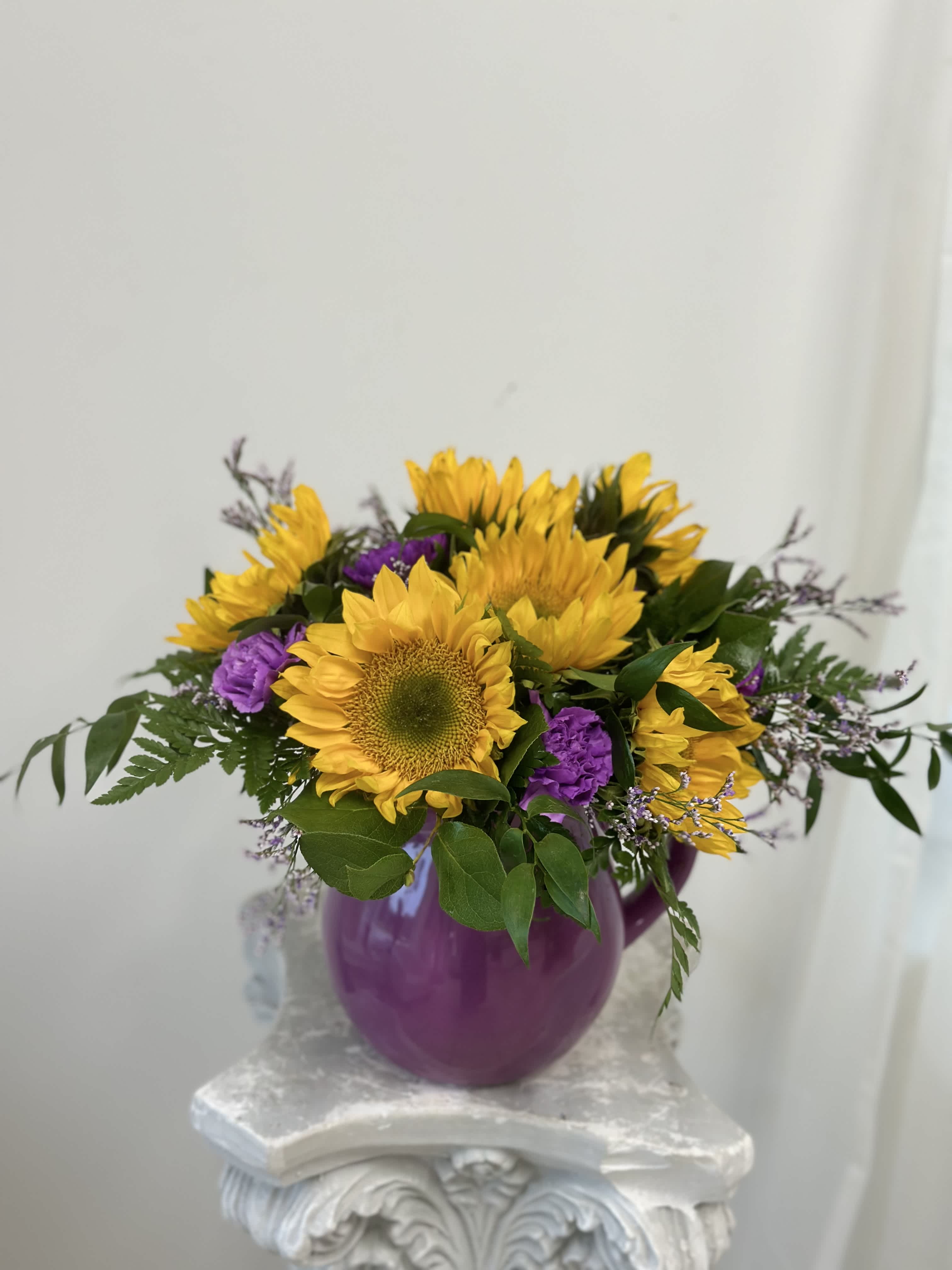 Summer Sunshine by Westford Florist Art by Veny - If you're looking to brighten up your living space with a touch of sunny serenity, Sunflower Serenade arrangement by Westford Florist Art by Veny is the perfect choice. This stunning arrangement features vibrant sunflowers, delicate sea lavender, and elegant carnations expertly arranged in a charming keepsake pitcher. Sunflowers are known for their cheerful and uplifting nature, making them the star of this arrangement. Their bold yellow petals radiate warmth and happiness, instantly bringing a sense of joy into any room. A symbol of loyalty and adoration, these flowers make the perfect gift for someone special or simply as a treat for yourself. To complement the sunflowers' vibrant color, our skilled florists have added delicate sea lavender to the mix. Also known as statice, these flowers add a touch of whimsy to the arrangement with their small clusters of purple or white blooms. So why wait? Order our Sunflower Serenade today and experience the joy it brings for yourself!