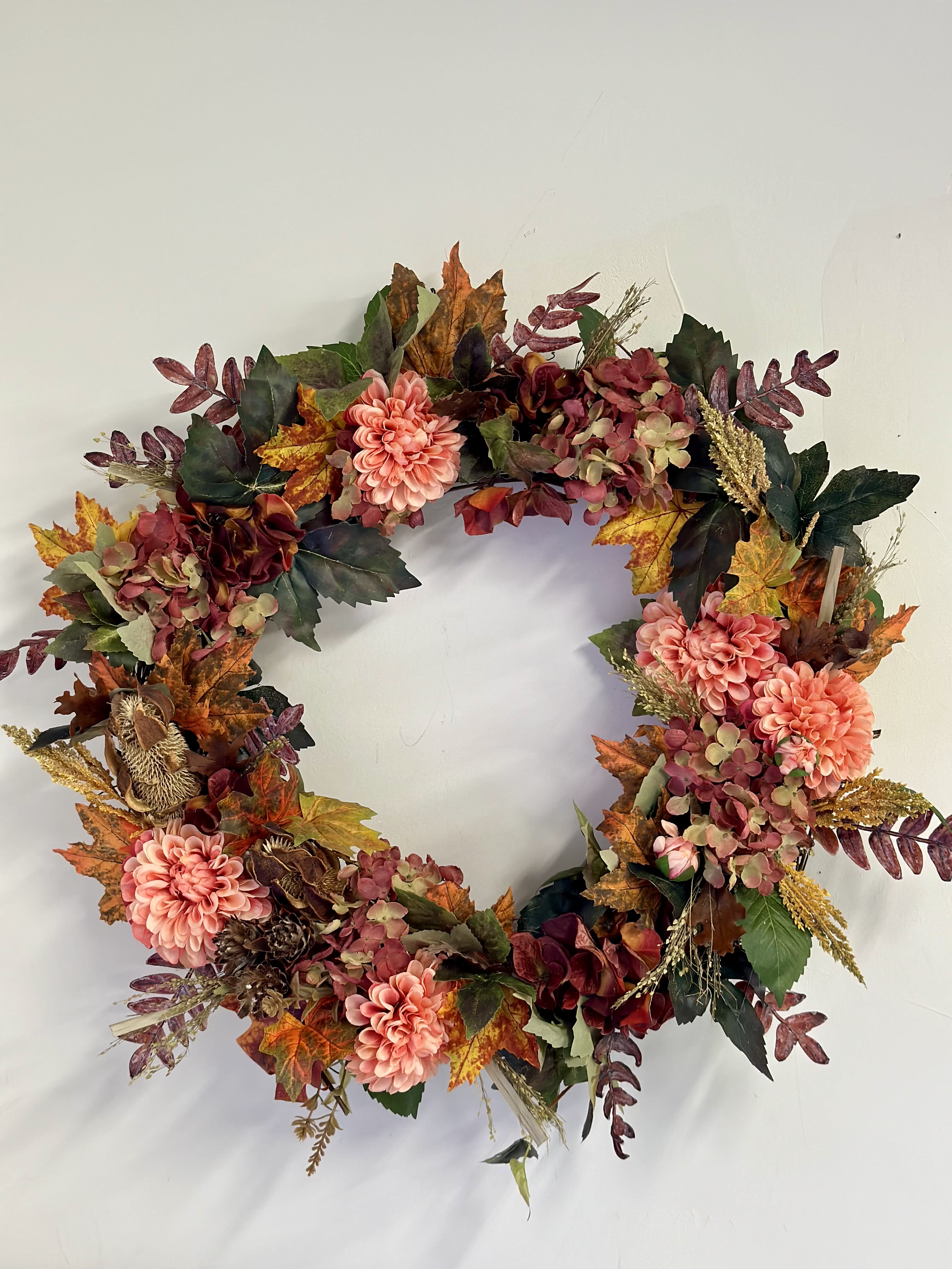 Fall Silk Wreath by Westford Florist Art by Veny - Embrace the beauty of autumn with our exquisite Fall Silk Wreath by Westford Florist Art by Veny. Meticulously crafted from a rich blend of vibrant seasonal foliage, this stunning décor piece captures the essence of harvest time with warm hues of orange, deep reds, and rustic browns. Ideal for adorning your doorway or enhancing your living space, it infuses your home with nature's splendor throughout the year. Measuring an impressive 22 inches in diameter, this silk wreath is not just a decoration; it's an invitation to celebrate cozy gatherings and cherished moments in every season. Elevate your environment and enjoy the enduring charm of fall at any time.