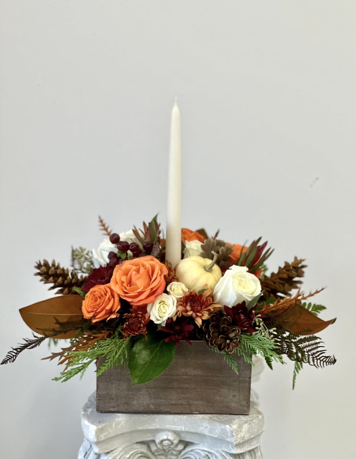 Rustic Chic Centerpiece by Westford Florist Art by Veny - Add elegance to your Holiday festivities with the Rustic Chic centerpiece by Westford Florist Art by Veny. This stunning arrangement boasts a perfect fusion of orange and white roses, along with delicate spray roses, safari sunset blooms, and elegant lisianthus. For an added touch of opulence, our premium option includes exquisite orchids to enhance the display. The centerpiece is thoughtfully placed in a beautifully crafted wooden box and adorned with tall candles that emit a warm ambiance over your table setting. Complete with magnolia leaves and vibrant autumn foliage, this centerpiece captures the essence of the season's splendor. Impress your guests this holiday with a centerpiece that exudes both charm and sophistication.