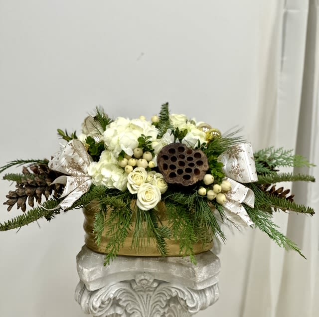 White Holiday Elegance by Westford Florist Art by Veny - Elevate your holiday decor with White Holiday Elegance by Westford Florist Art by Veny!  This stunning arrangement features delicate hydrangeas, gracefully nestled in a festive ceramic pot that instantly radiates seasonal cheer. With the enchanting combination of vibrant spray roses, charming hypericum berries, playful poms, and unique lotus pods—each detail is curated to bring joy to your space. Topped off with natural pinecones and a lush Christmas ribbon, this centerpiece is not just a decoration; it’s an invitation to celebrate! Perfect for gifting or as a splendid treat for yourself, let Holiday Harmony infuse your festivities with warmth and beauty. Order now and bask in the glow of holiday magic! 