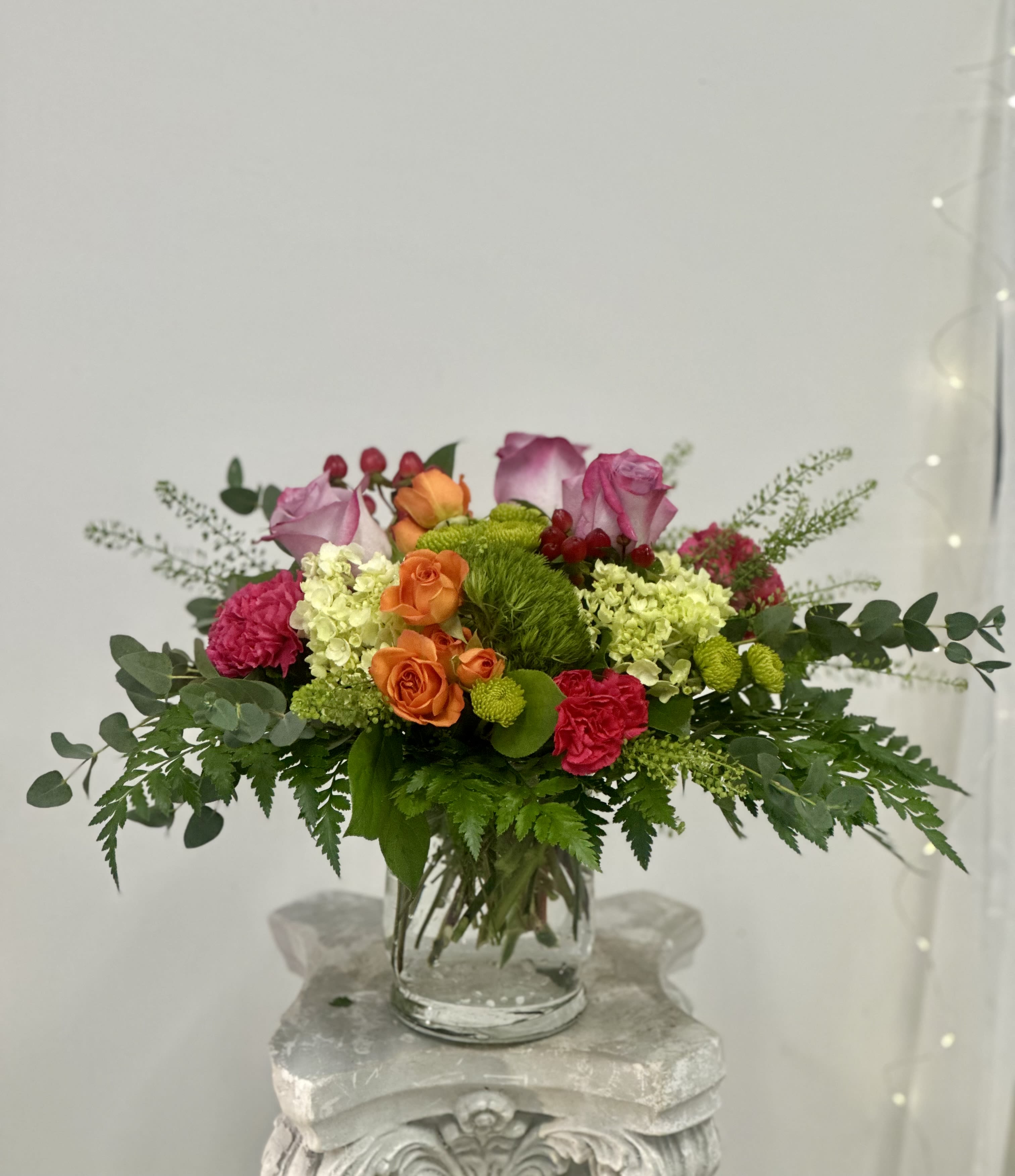 Mixed pink, orange, and green flower arrangement in a clear glass vase