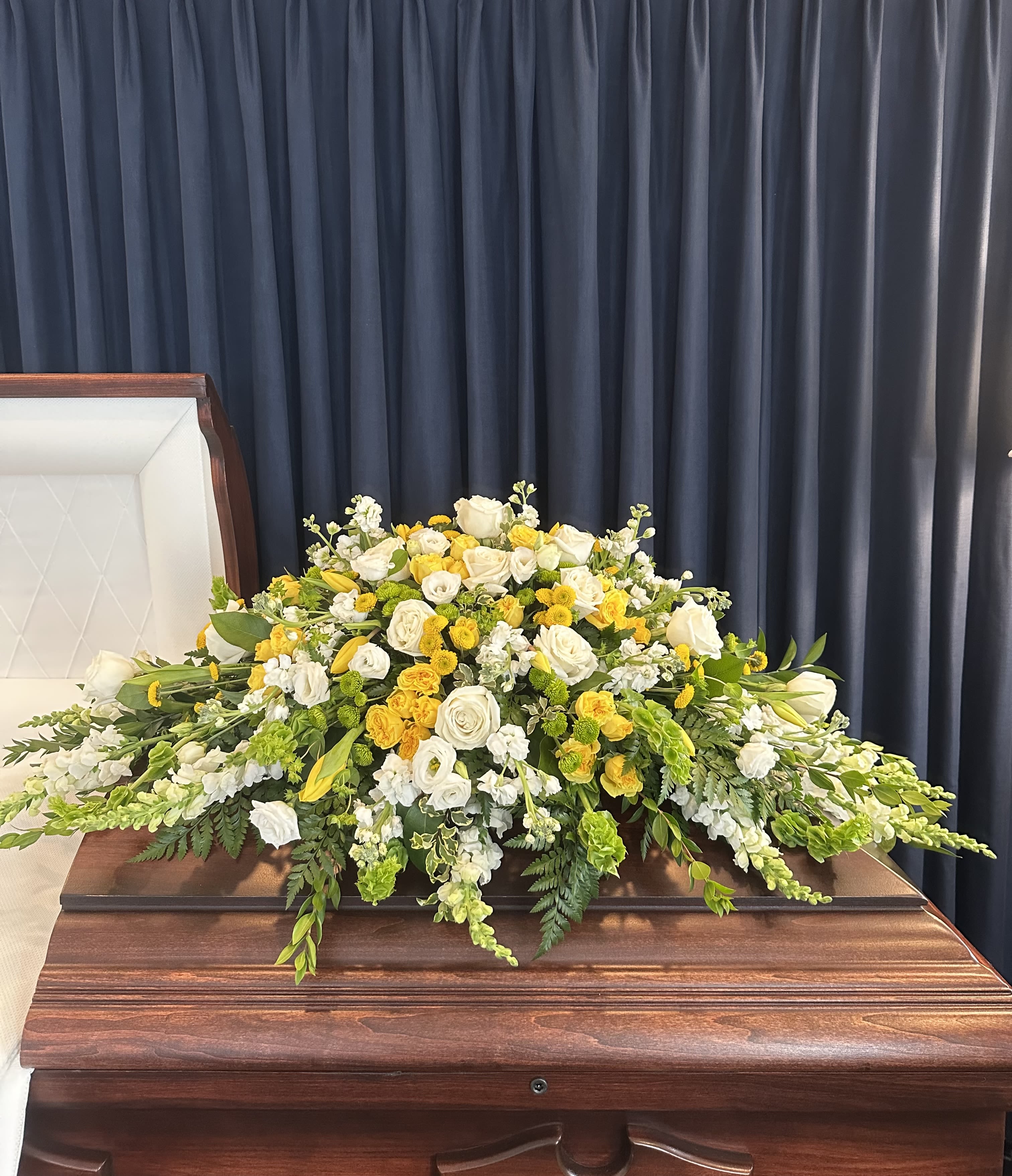 White and yellow floral spray on a casket