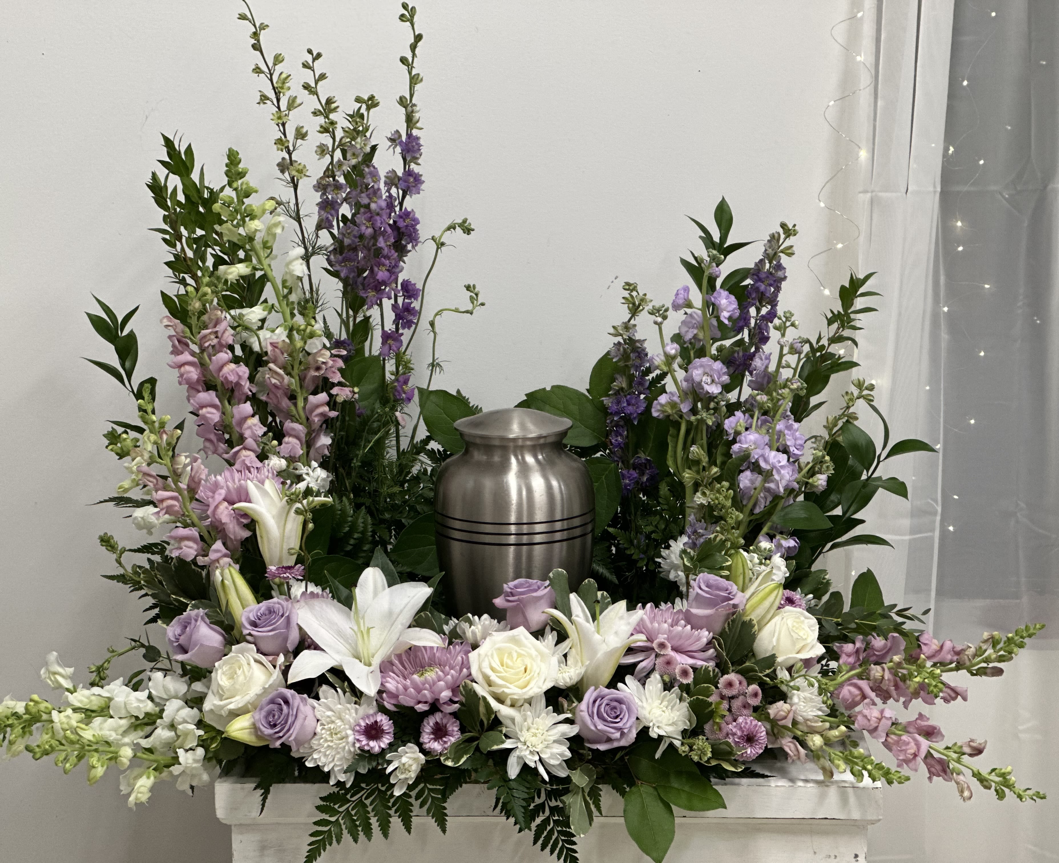 Lavender and white floral arrangement around a silver urn