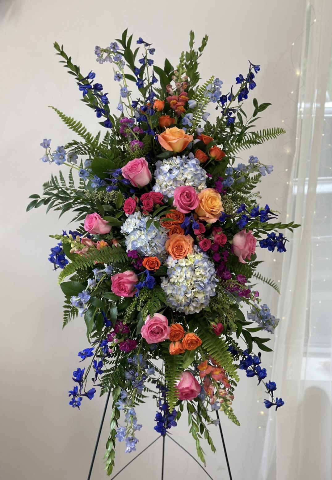 Tall standing floral spray with pink, orange, blue, and lavender blooms