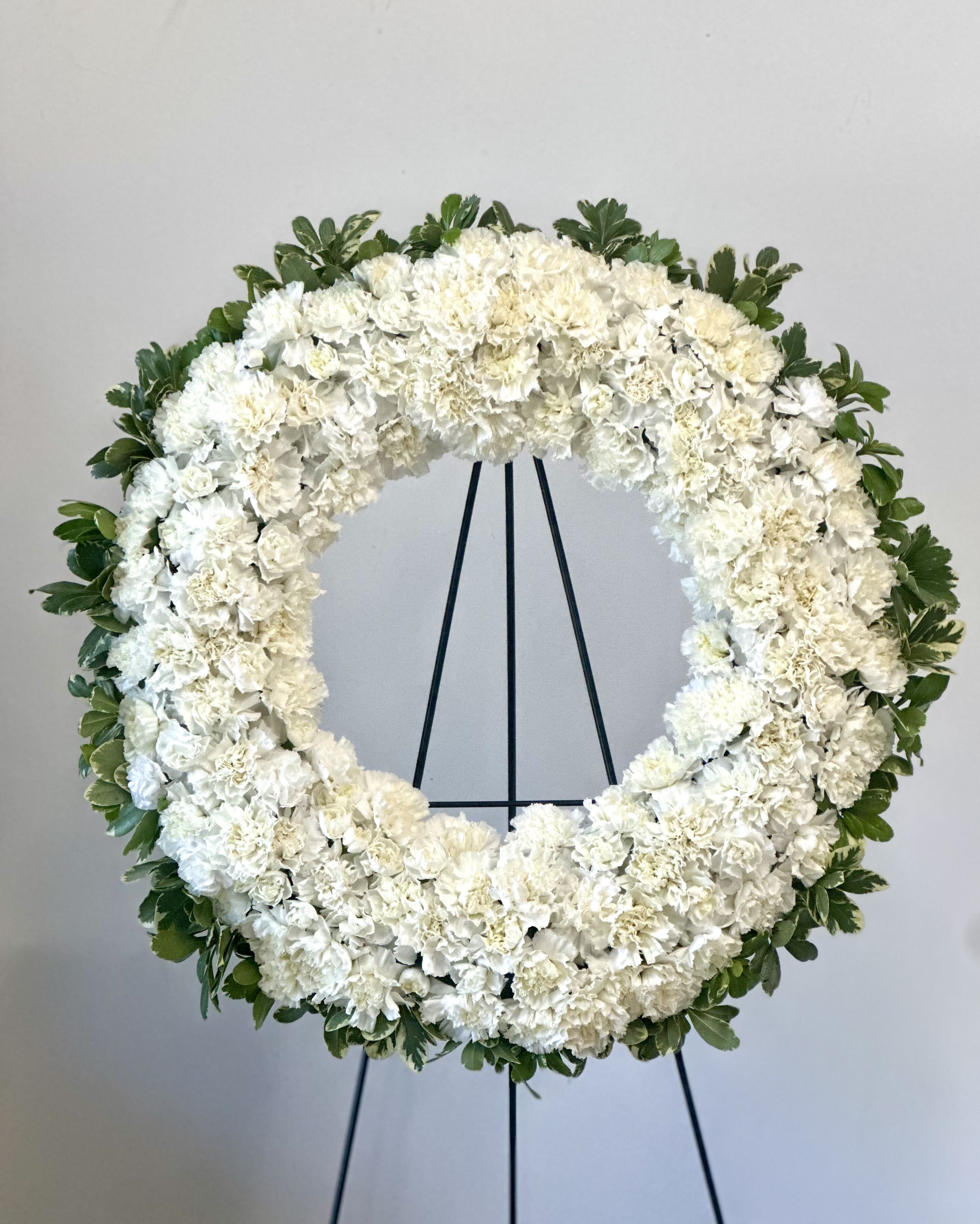 White floral wreath on a black stand