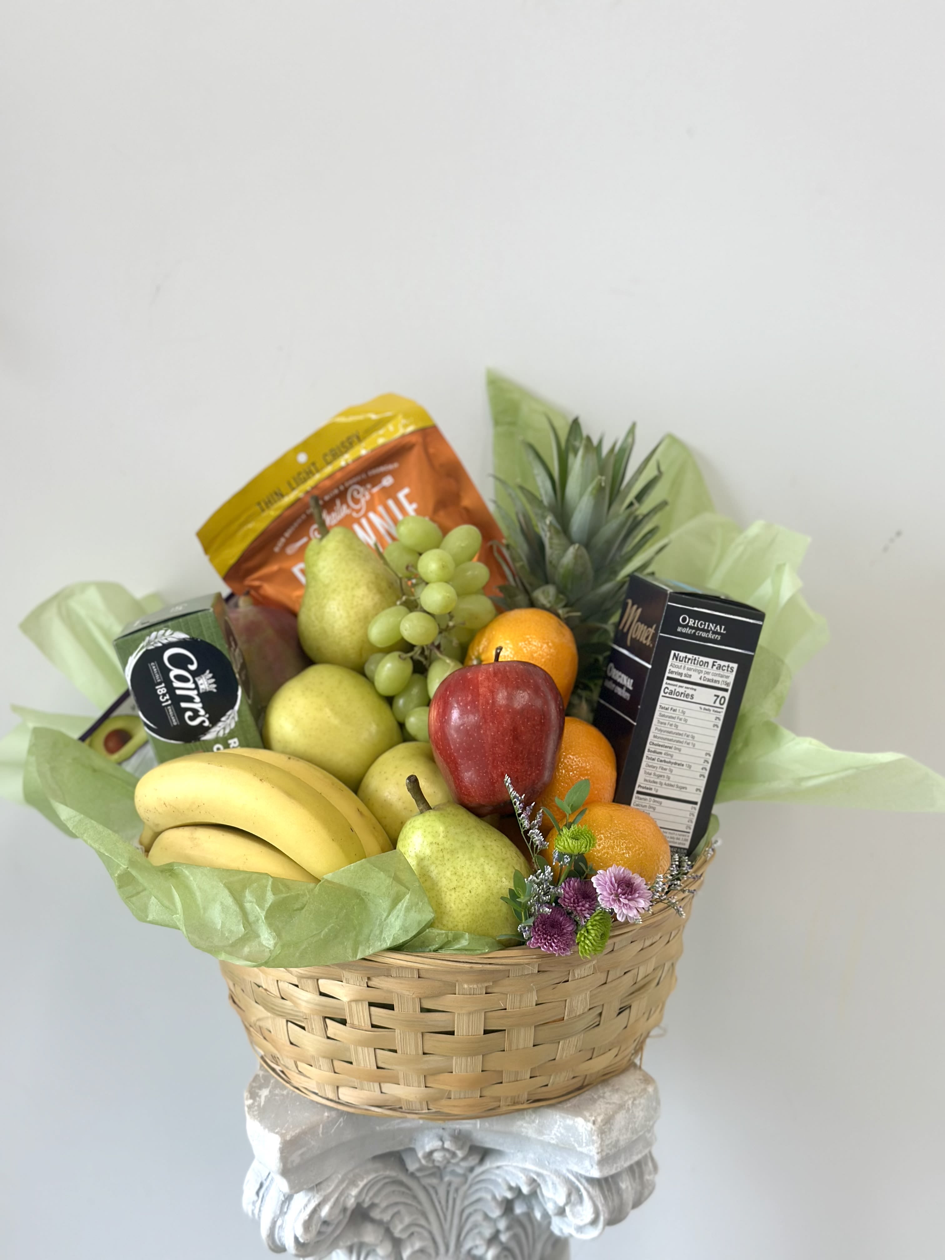 Fruit basket with bananas, pears, grapes, oranges, and snack boxes