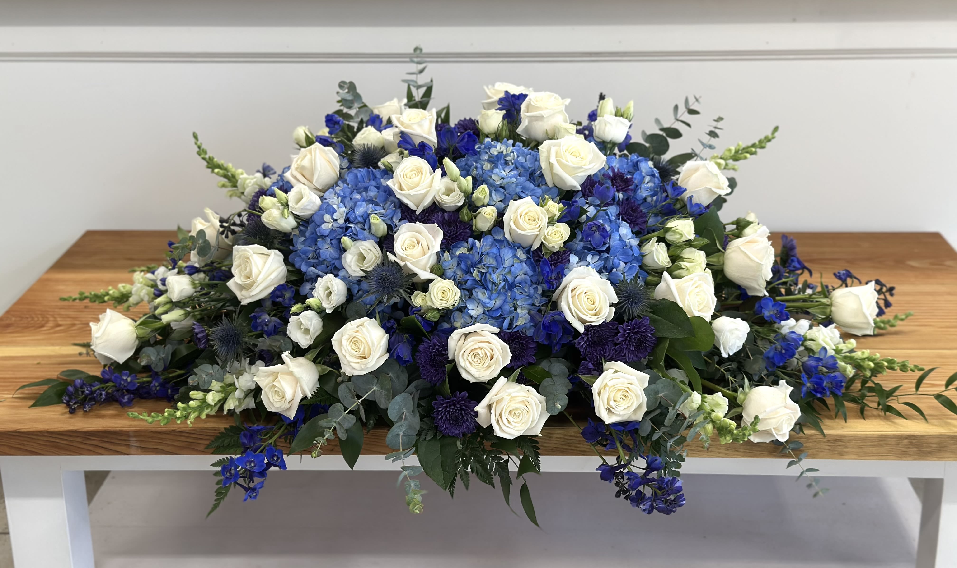 Blue and white floral arrangement with roses and hydrangeas on a table