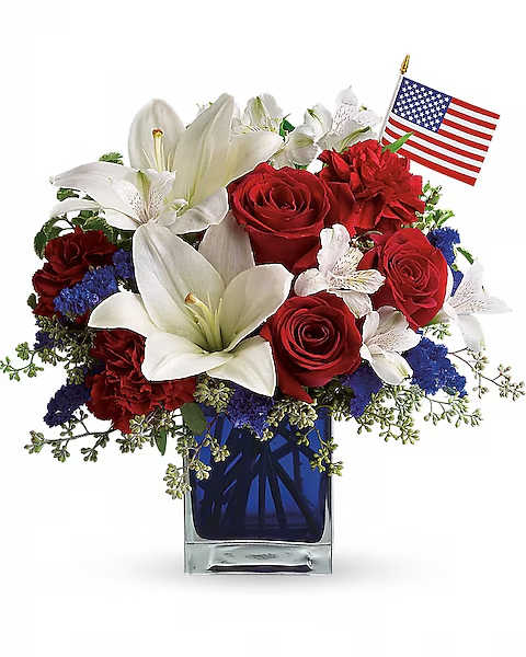 Red roses and white lilies in a blue glass vase with a small American flag