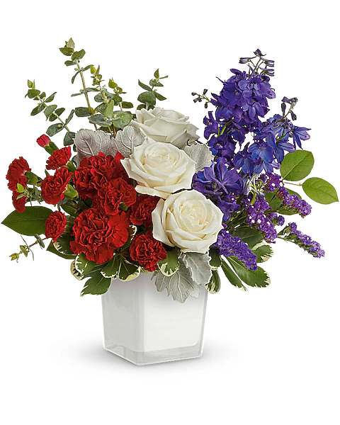 Red and white roses with purple flowers in a clear square vase