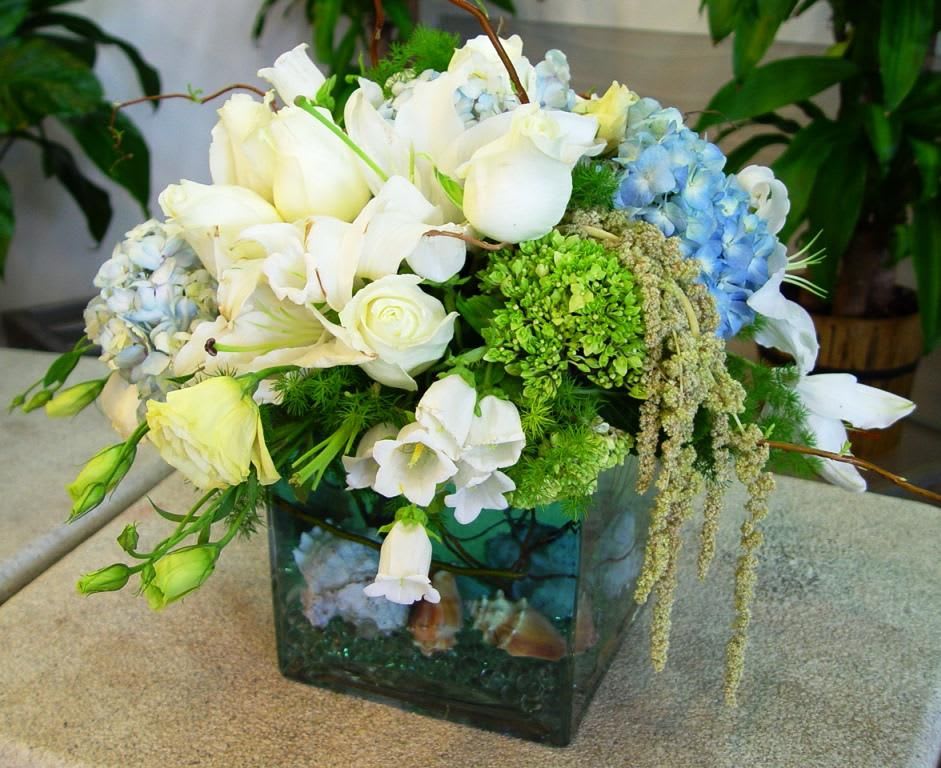 White and blue floral arrangement in a square glass vase