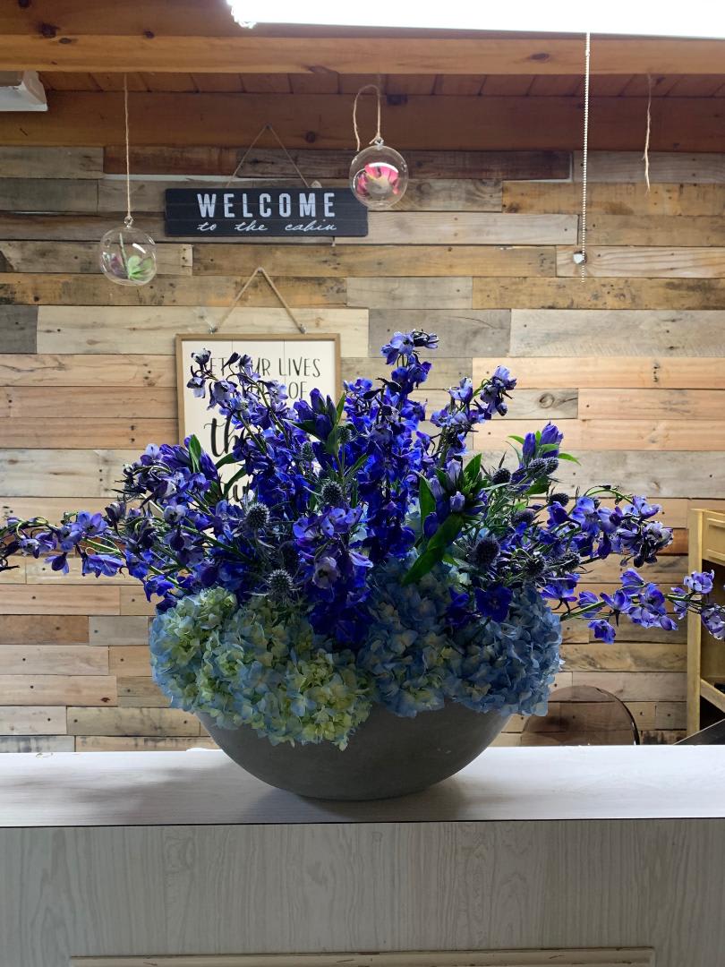 Blue and purple floral arrangement in a round vase