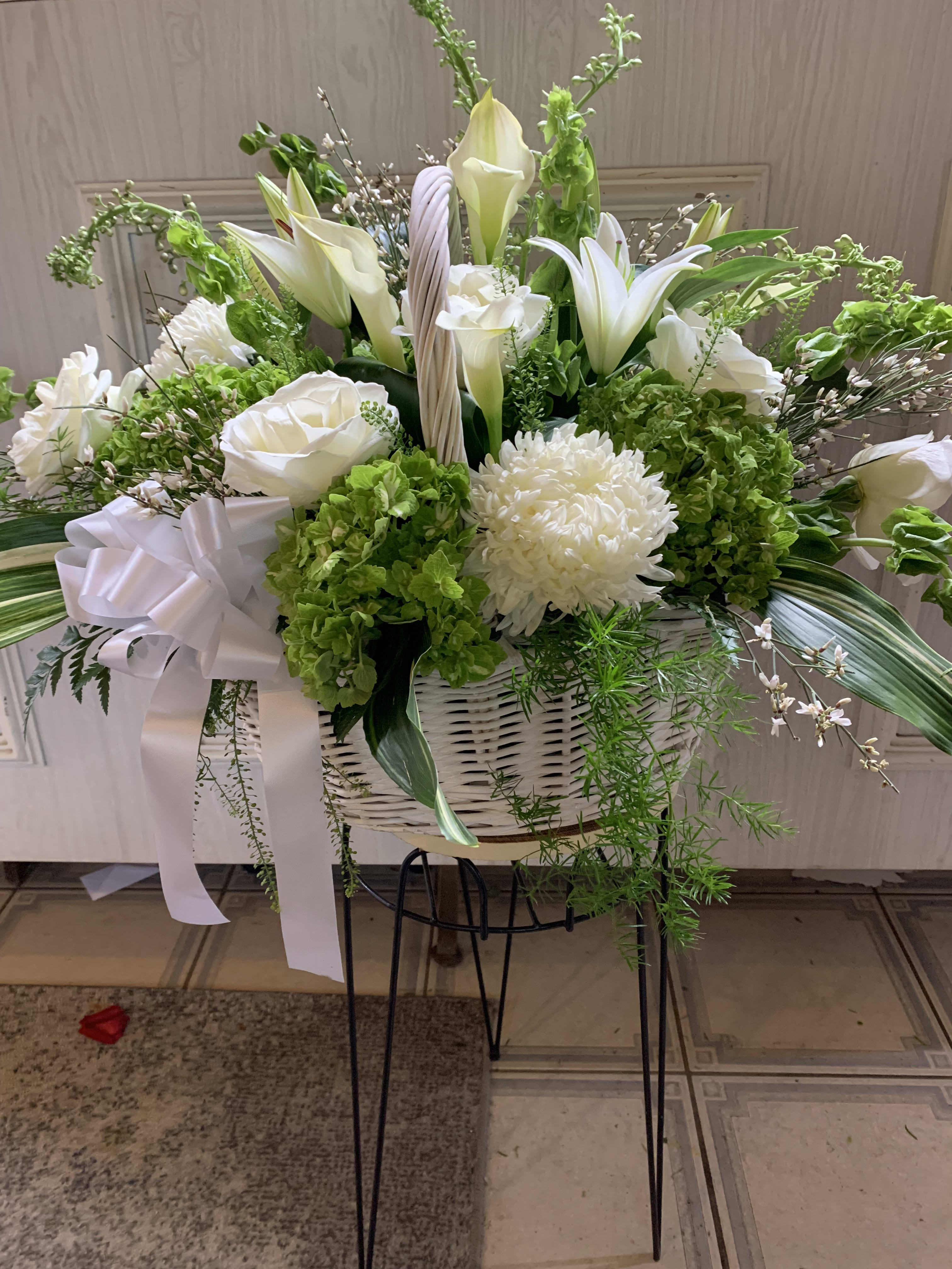 White lilies and chrysanthemums in a white basket with a ribbon