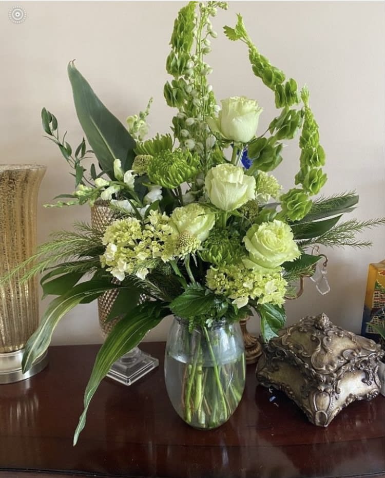 Green and white floral arrangement in a glass vase