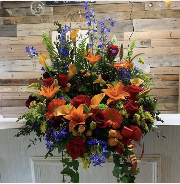 Large mixed bouquet with red roses, orange lilies, and blue flowers
