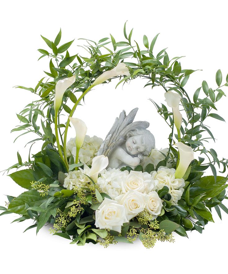 White roses and calla lilies arranged around a sleeping angel figurine