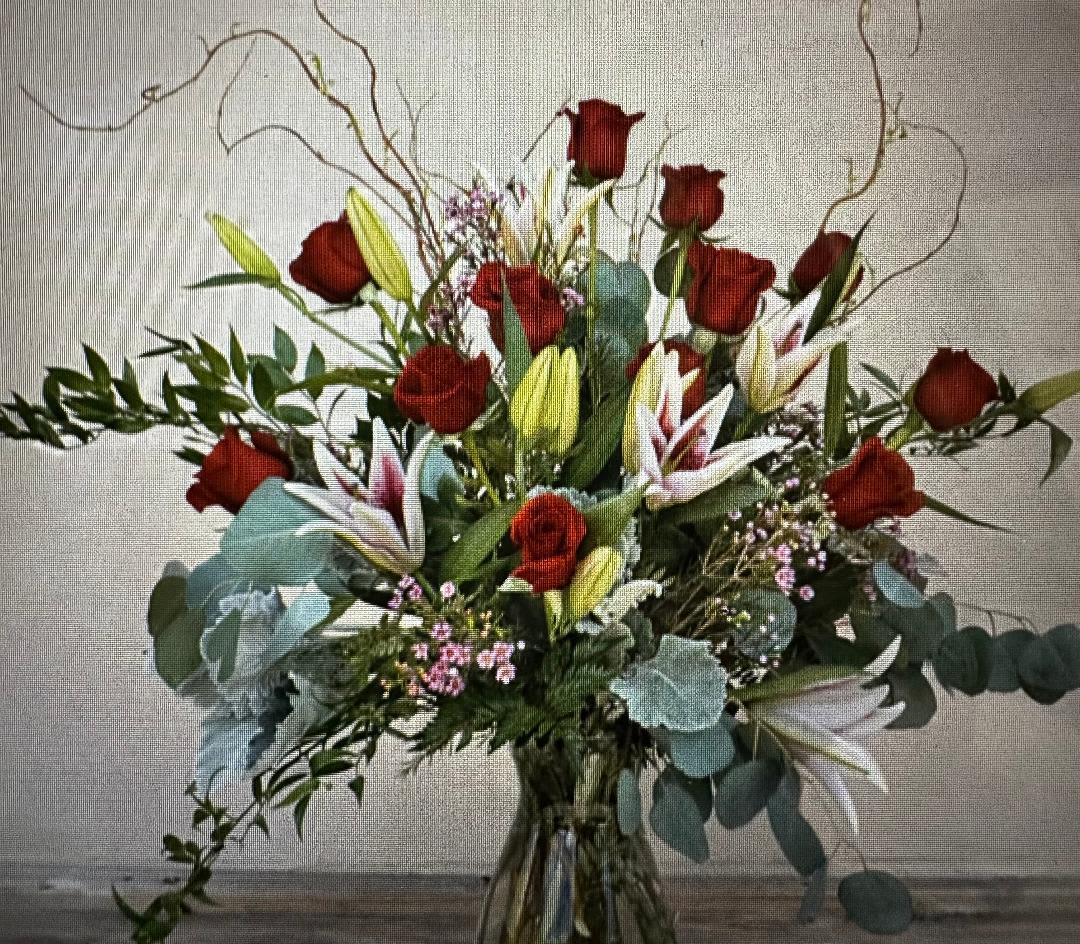 Red roses and lilies in a clear glass vase