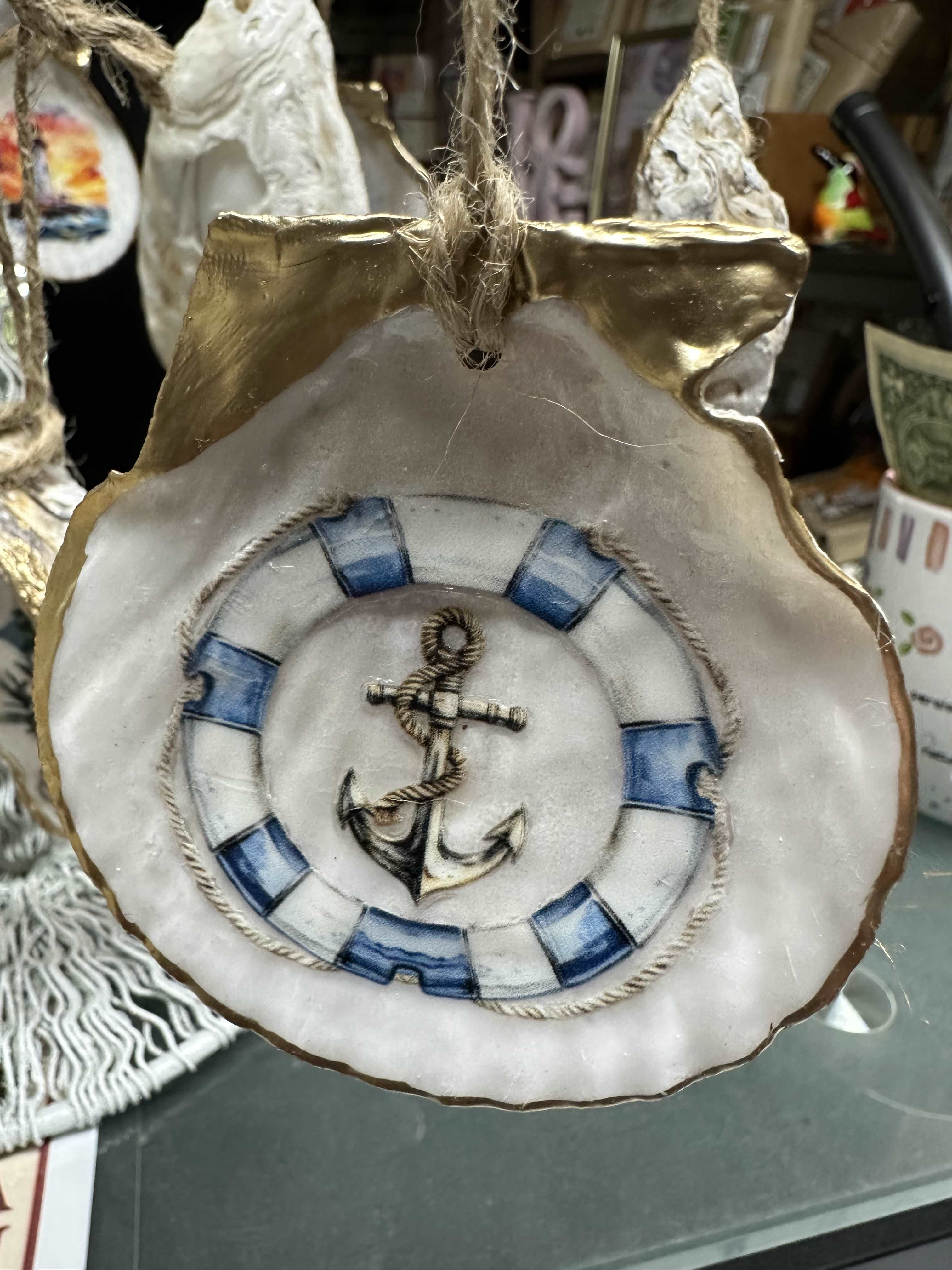 Decorative hanging ornament shaped like a shell with an anchor design