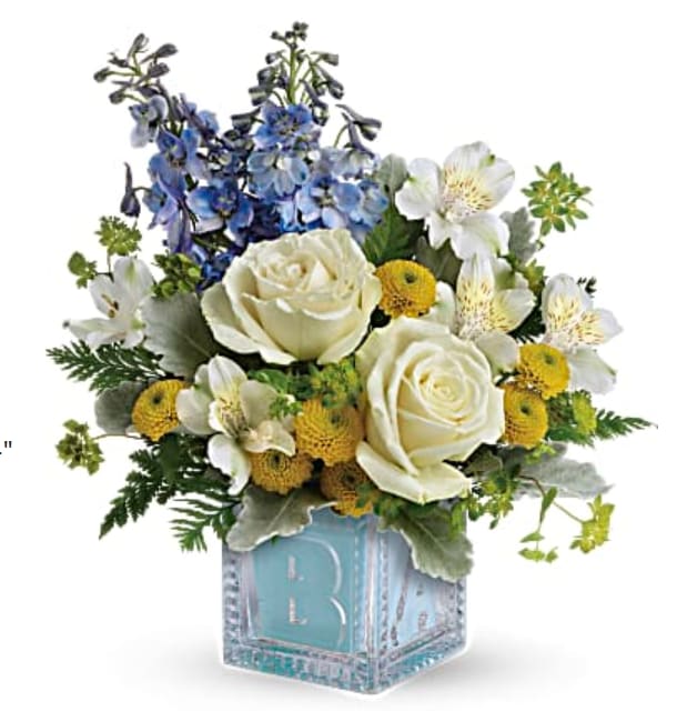 White roses and blue flowers in a blue cube vase