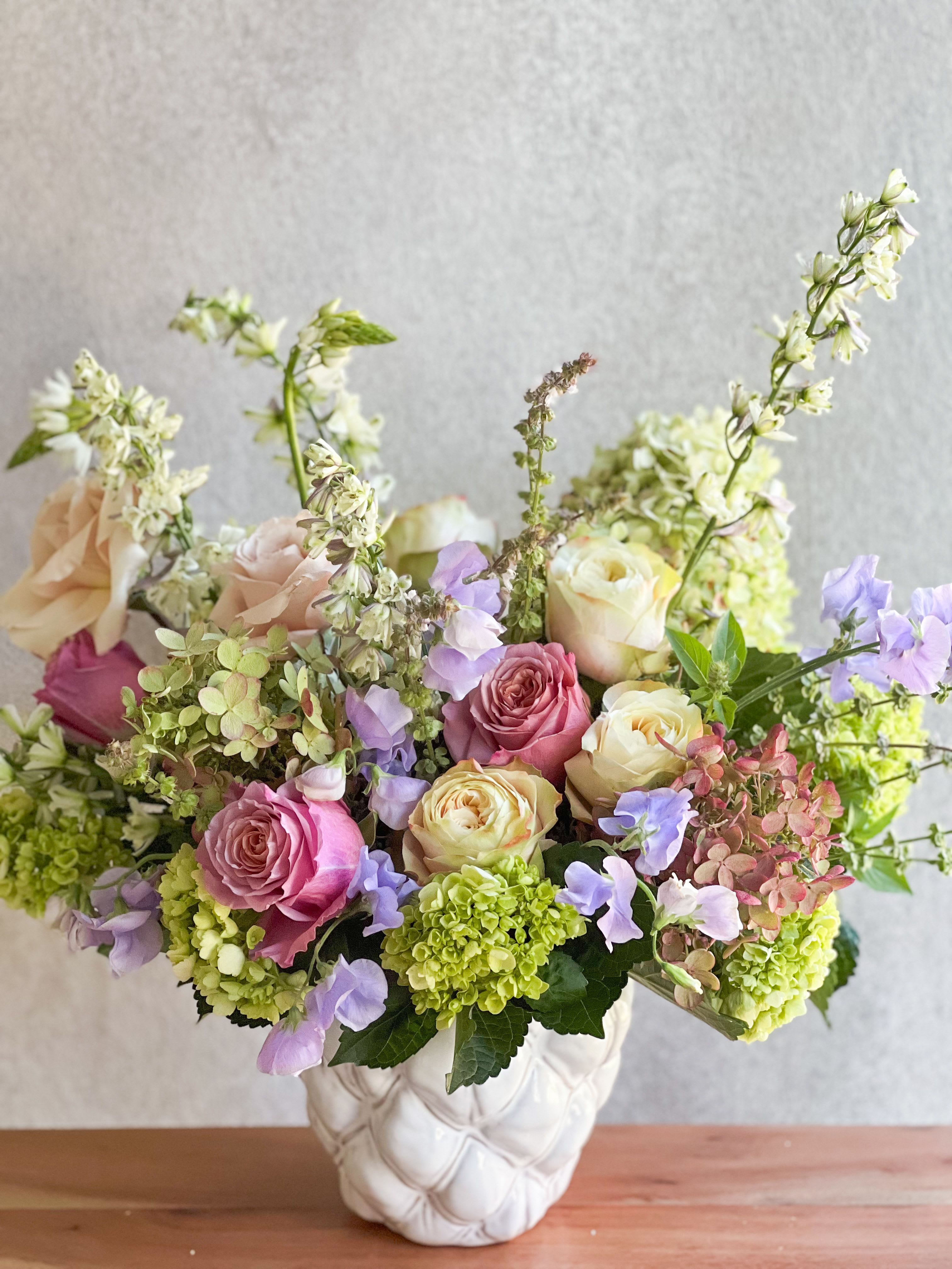 Mixed pink and cream roses in a white vase with lavender flowers