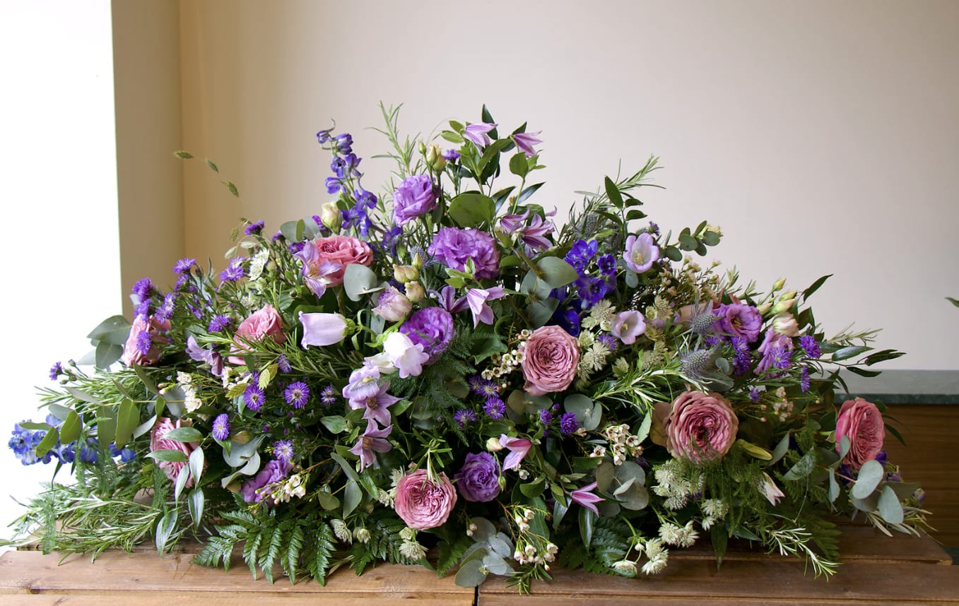 Casket Spray in shades of Lavender - Our casket spray flowers are meticulously crafted arrangements specifically designed to rest upon the casket during a funeral or memorial service.   This is in shades of lavender/ purple.   Pictured is the standard size 