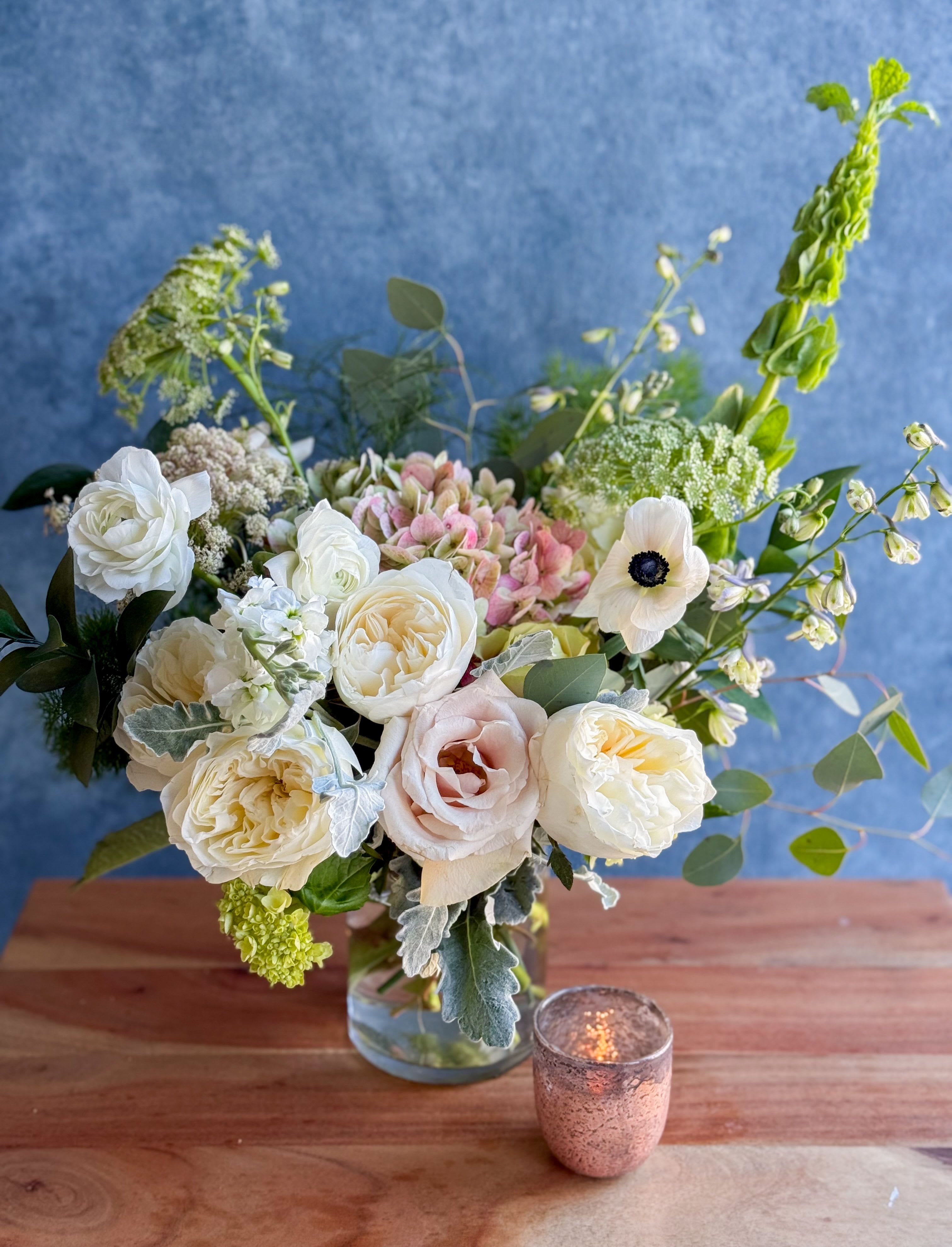 White and blush roses in a glass vase with airy greenery