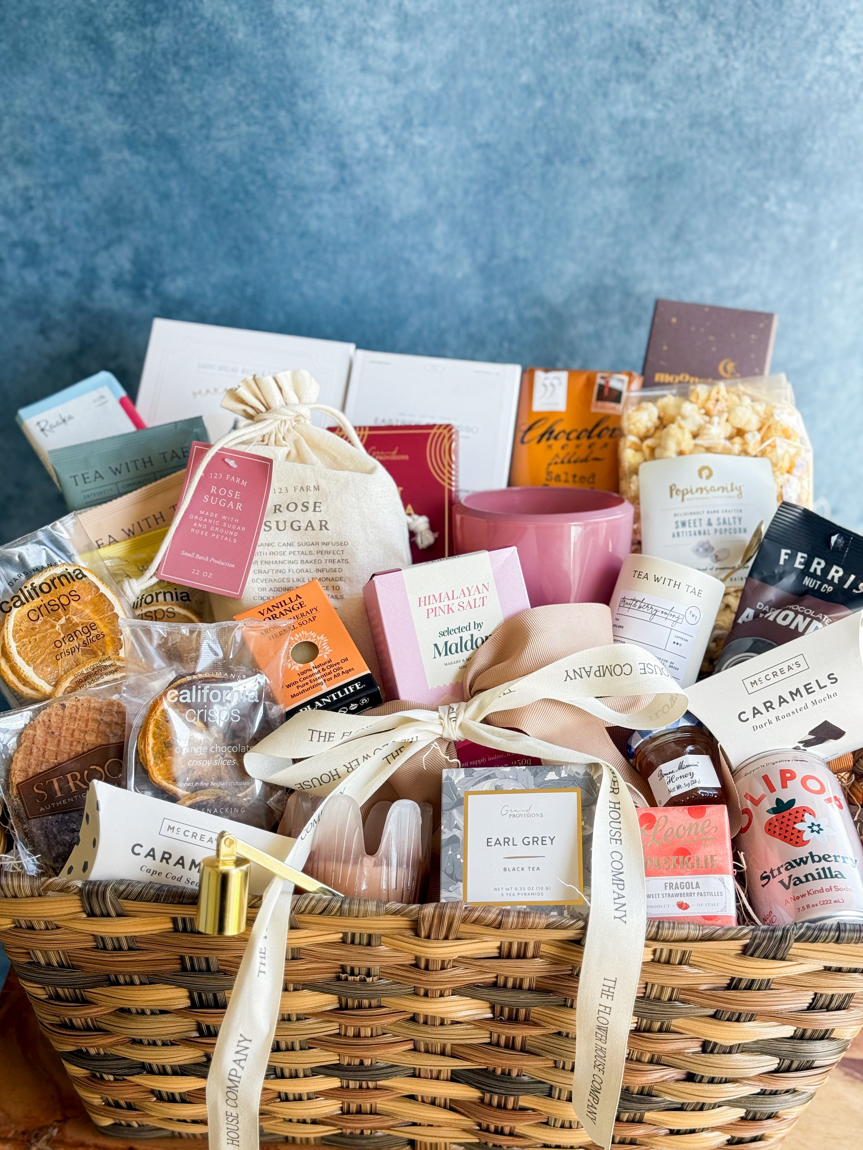 The Grand Gift Basket  - Make a grand impression with our Jumbo Gift Basket, overflowing with a wonderful assortment of sweet treats, cozy comforts, and thoughtful goodies. Beautifully arranged in a large basket, this generous gift is filled with a variety of items perfect for sharing, relaxing, and enjoying. Inside you’ll find a delightful mix of indulgent chocolates, crunchy snacks, gourmet treats, fragrant candles, artisan soaps, and rich, flavorful coffee. Each basket is thoughtfully curated to create a balanced blend of delicious flavors and comforting self-care items, making it a truly special gift. Finished with decorative ribbon, our Jumbo Gift Basket arrives ready to impress. Perfect for celebrations, holidays, corporate gifts, or simply sending a warm and thoughtful surprise, this abundant basket is sure to brighten anyone’s day. 