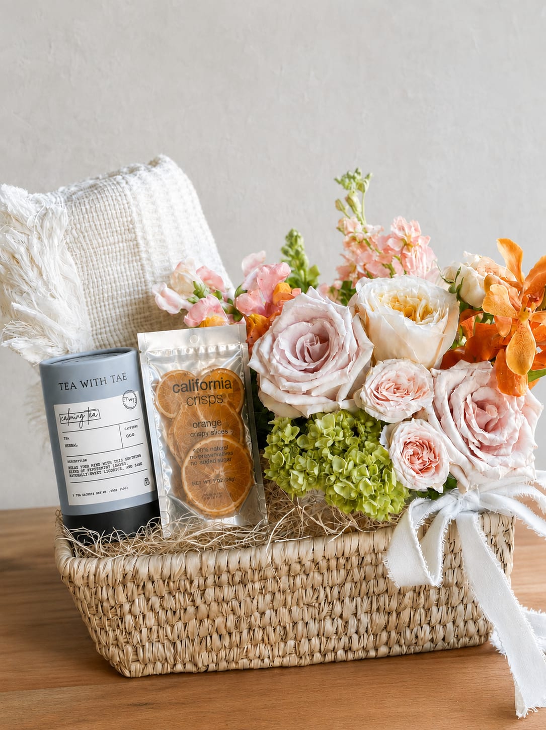 Flower gift basket with roses, hydrangeas, tea, and dried orange slices