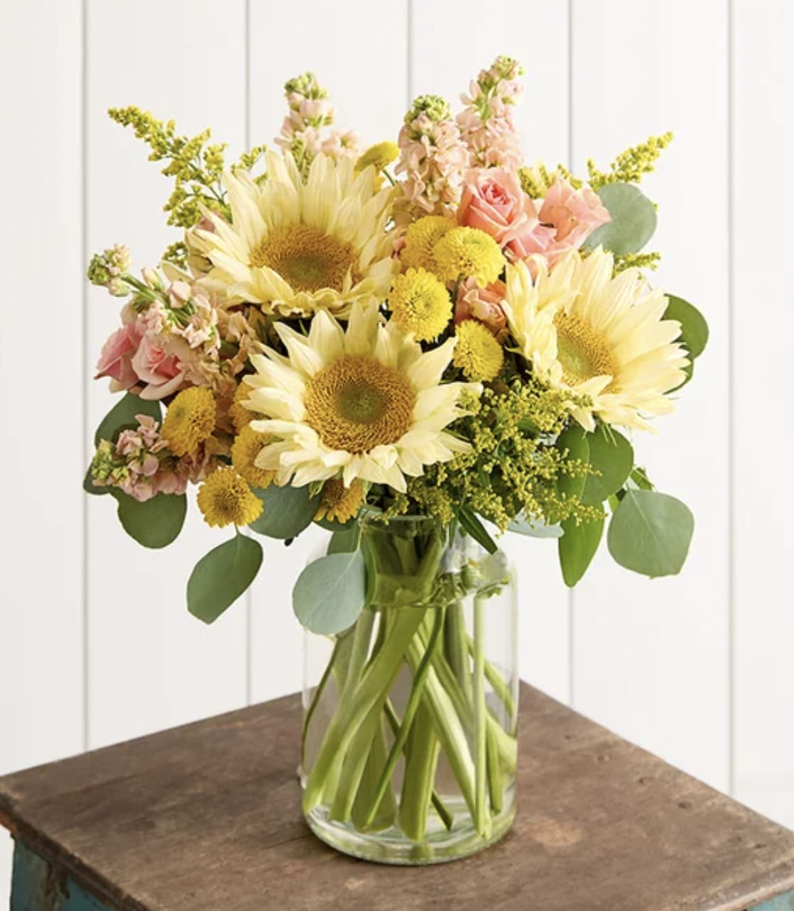 Sunflower bouquet with pink roses and yellow button flowers in a glass vase