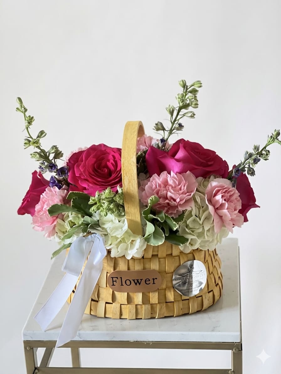 The Magenta Muse Basket - A stunning, hand-arranged bouquet bursting with vibrant magenta roses, delicate blush carnations, and lush white hydrangeas. Beautifully styled in a charming, keepsake woven basket with a crisp white satin bow, this elegant arrangement is the perfect gift for birthdays, anniversaries, or special celebrations.