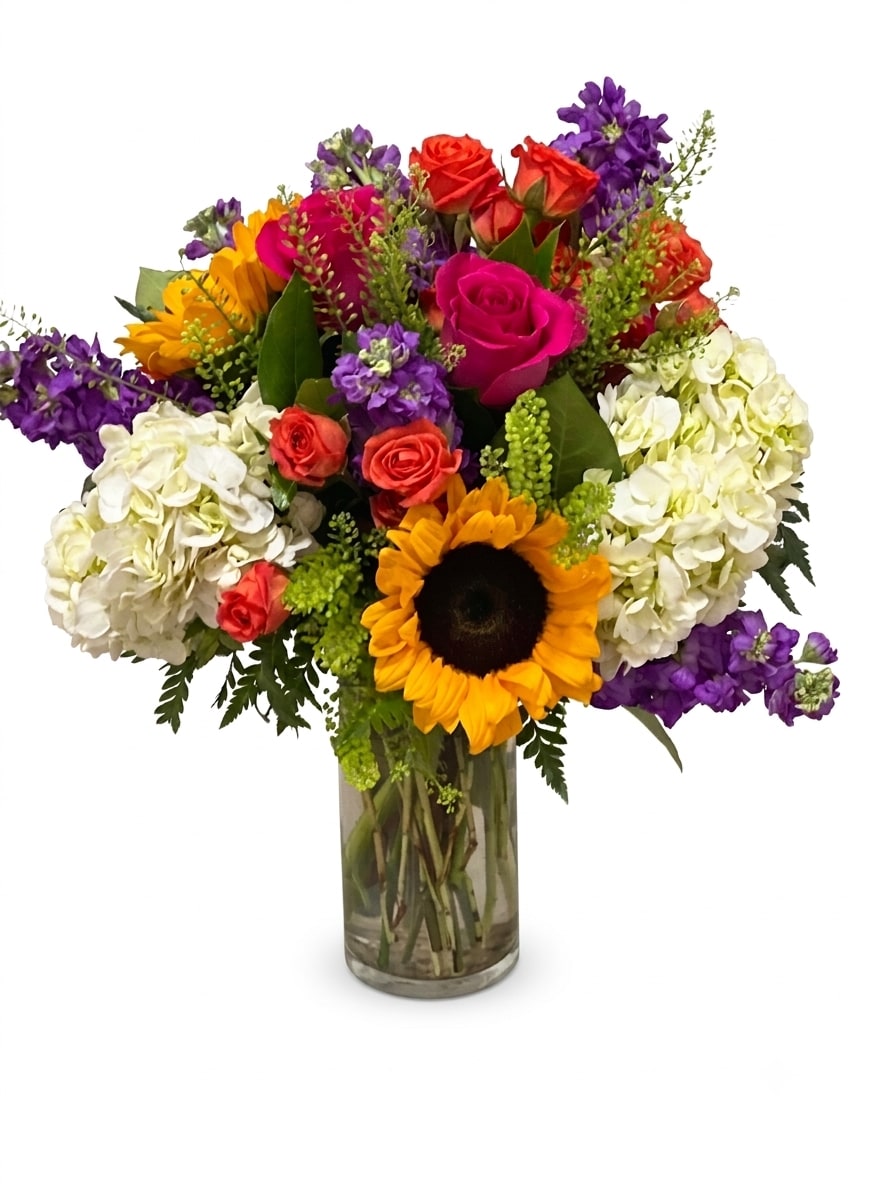 Colorful bouquet with roses, hydrangeas, and a sunflower in a glass vase