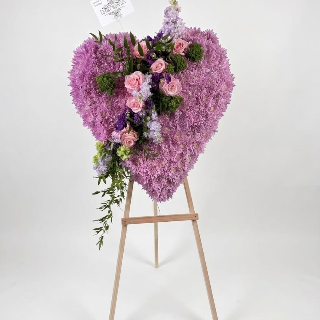 Heart-shaped pink floral arrangement on a wooden easel