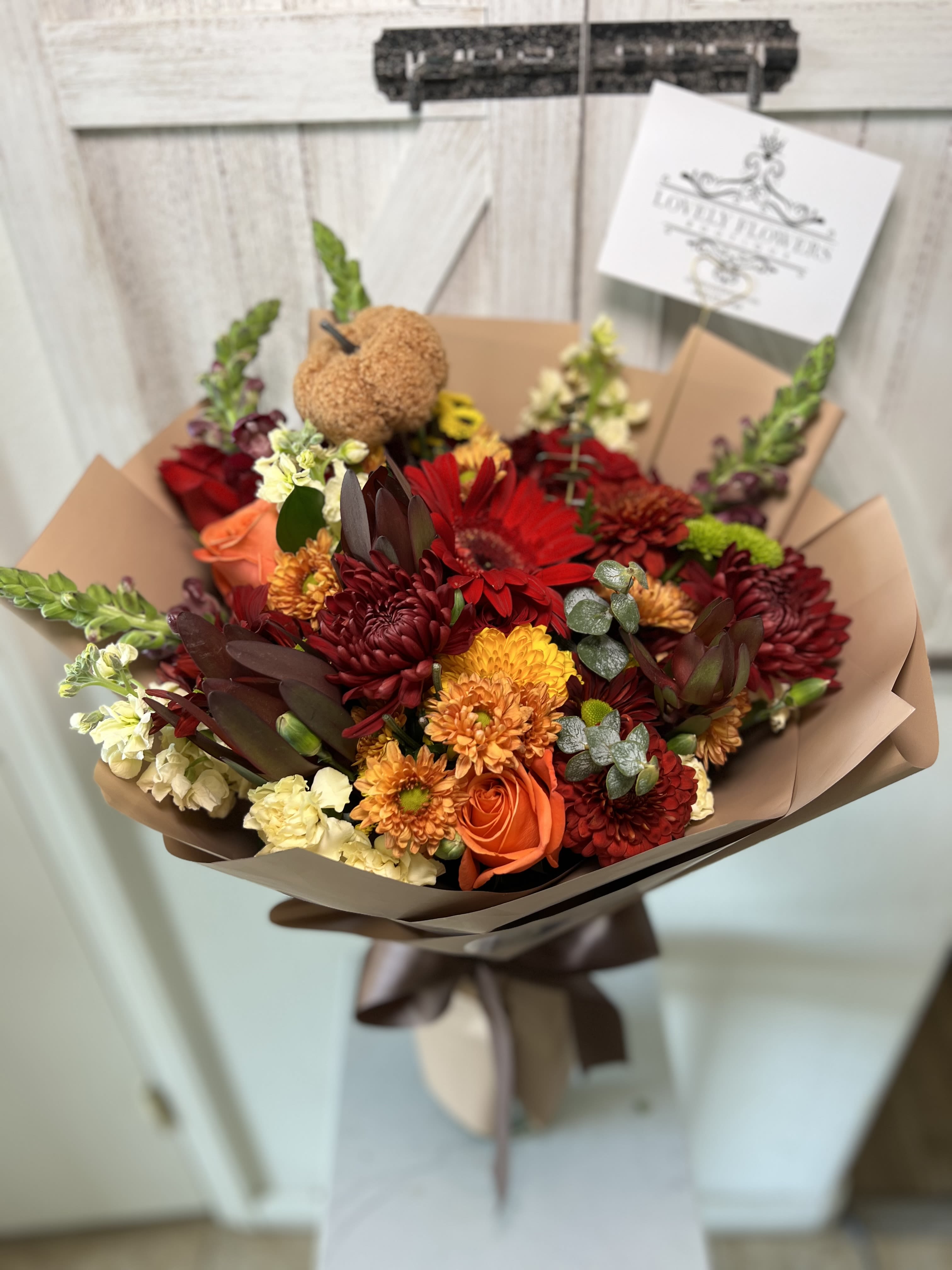 Bouquet of red, orange, and cream flowers wrapped in brown paper
