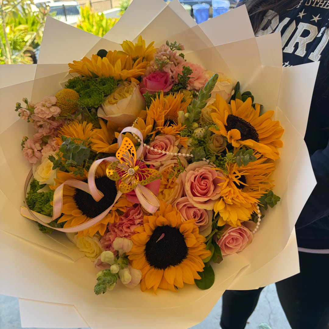 Bouquet of sunflowers and pink roses wrapped in white paper