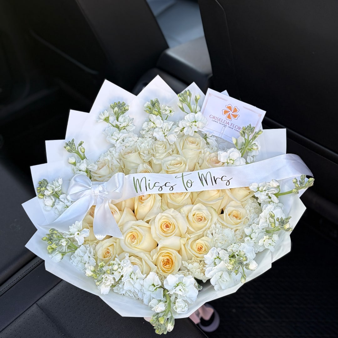 Cream rose bouquet with white flowers and a satin ribbon reading "Miss to Mrs"