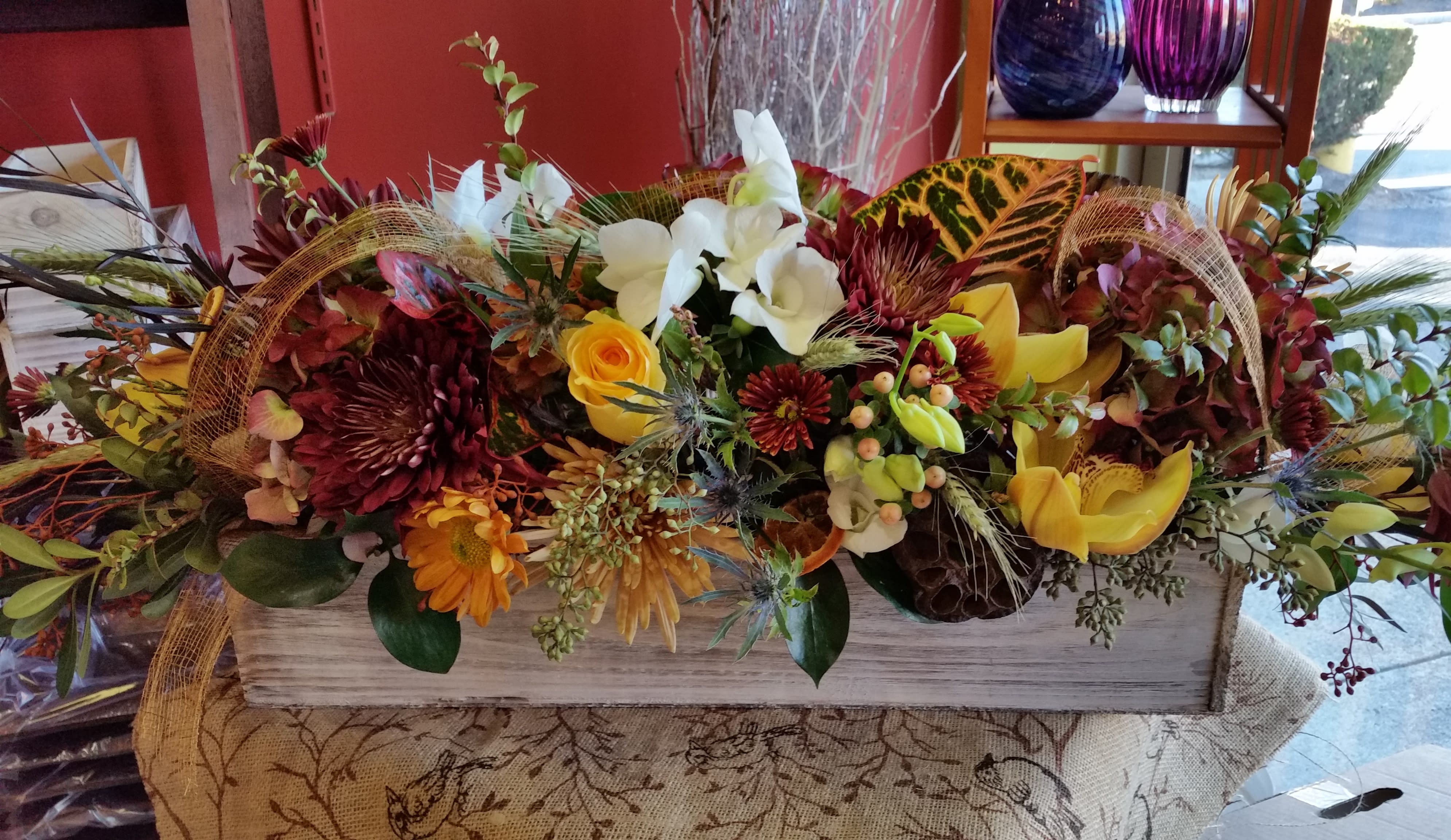 Large autumn floral arrangement in a rectangular wooden box with yellow and white blooms
