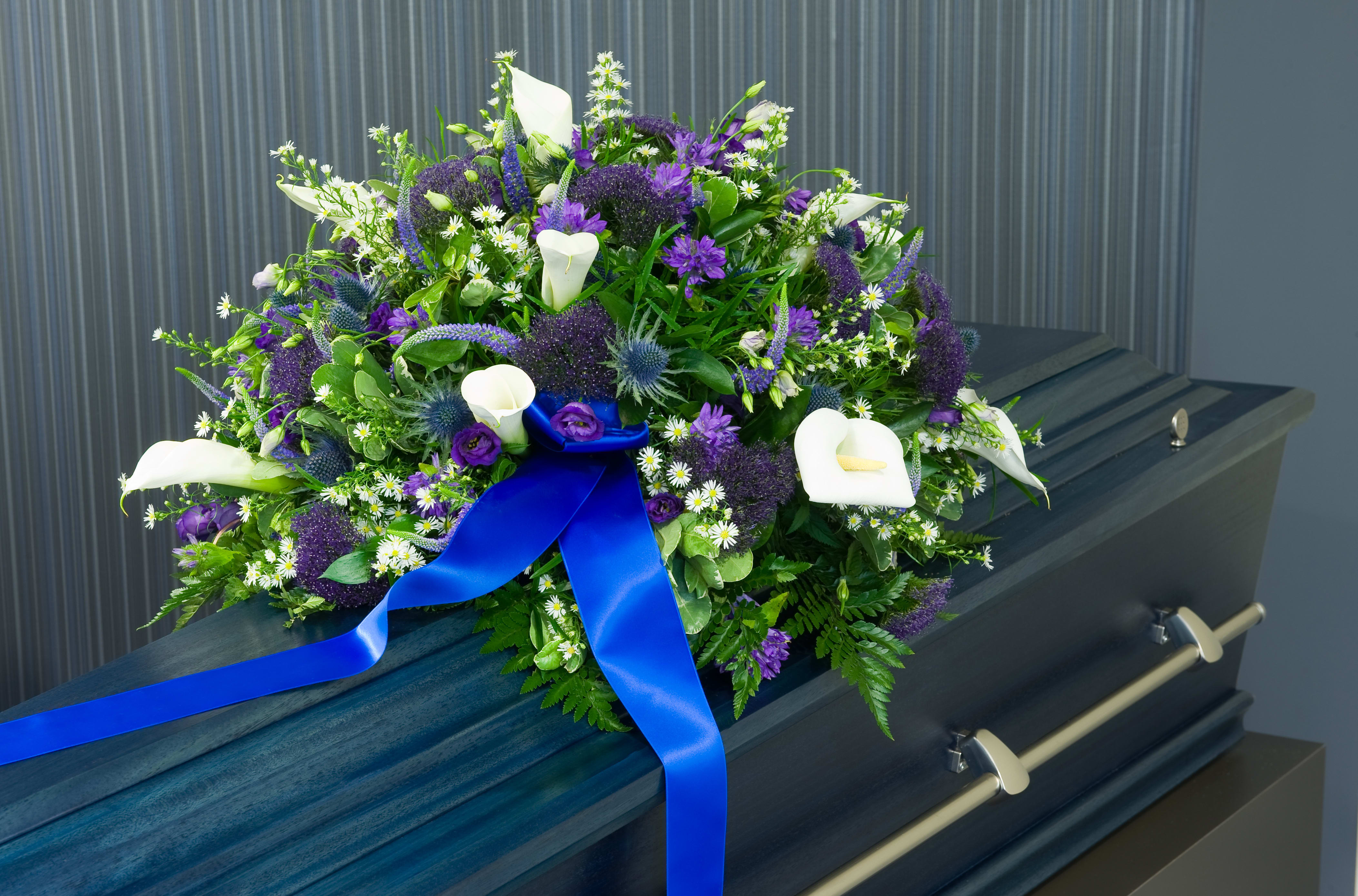 Purple and white funeral spray on a casket with a blue ribbon