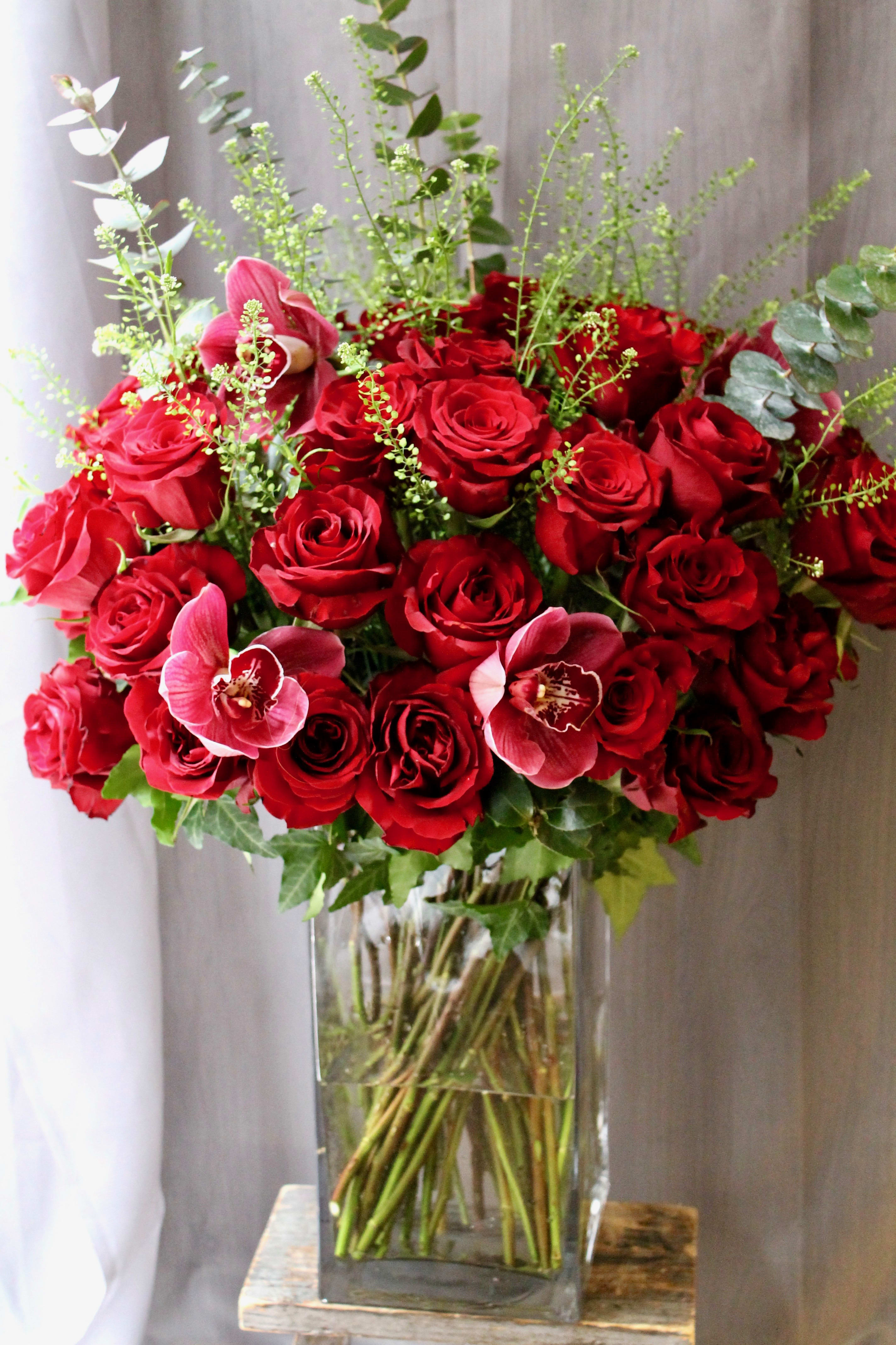 Red roses and pink orchids in a clear glass vase