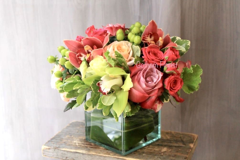 Mixed pink and red flower arrangement in a square glass vase