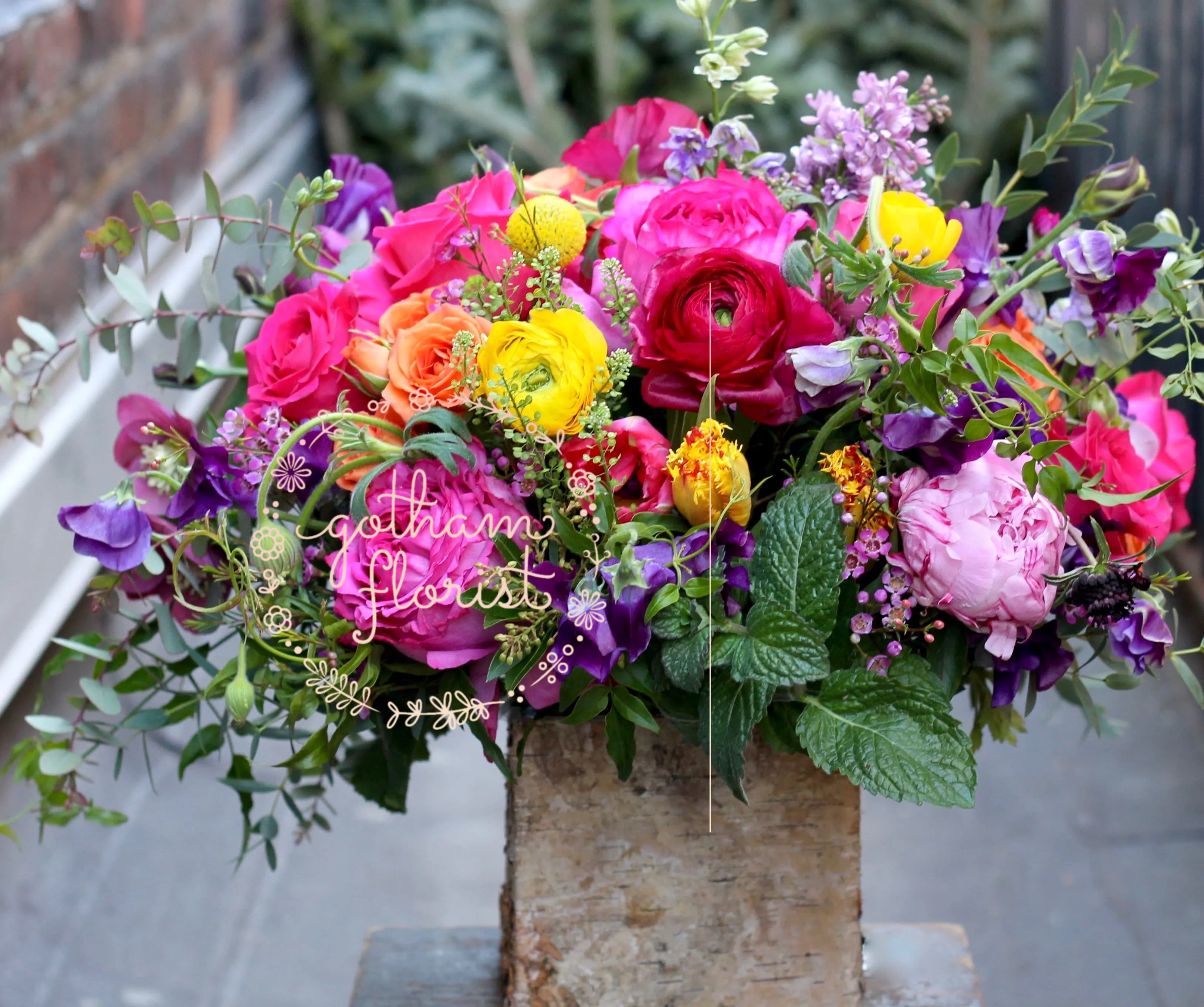 Bright mixed bouquet of roses and ranunculus in a rustic vase