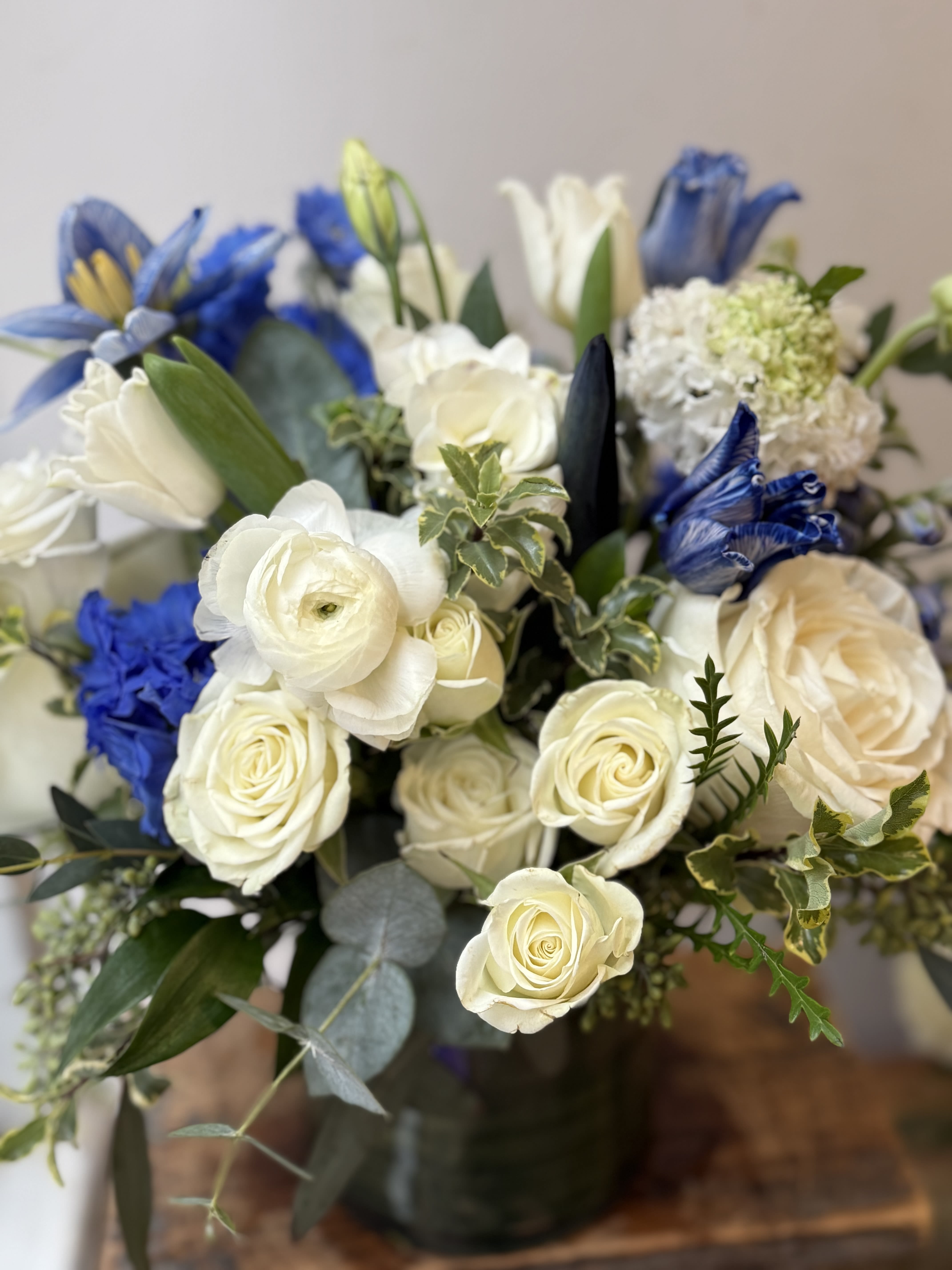 Bouquet of white roses and blue flowers with greenery