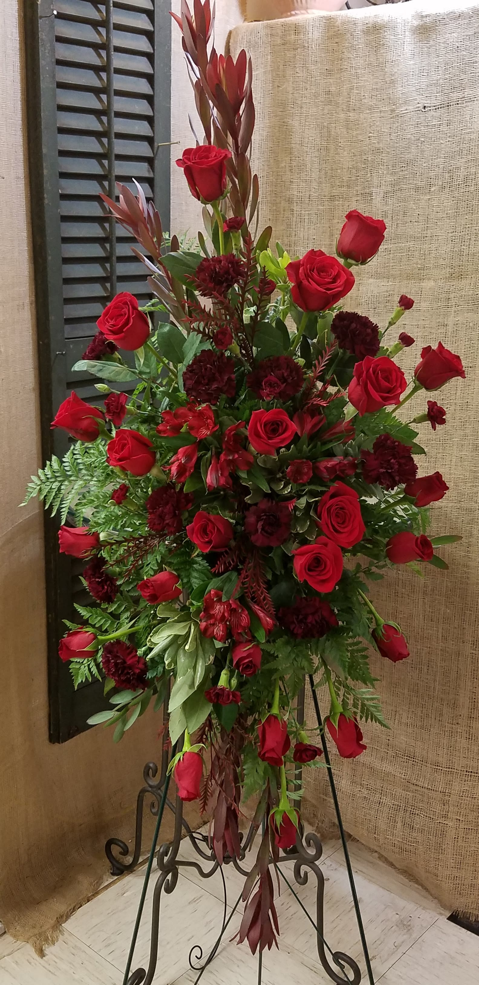 Tall red rose and burgundy floral standing arrangement on an easel