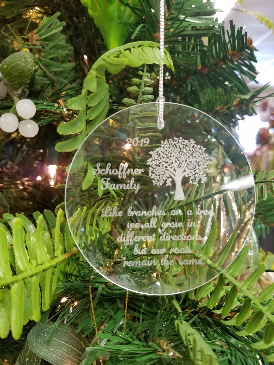 Clear ornament hanging on a Christmas tree with engraved text