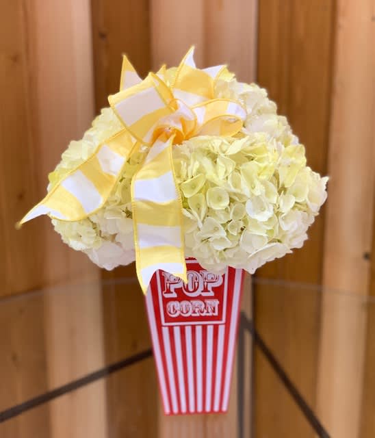 White hydrangea arrangement in a popcorn container with a yellow ribbon