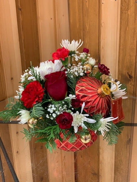 Red and white floral arrangement with ornaments in a decorative container