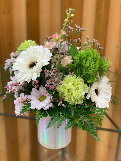 Pastel flower arrangement in a white vase with white daisies and green carnations