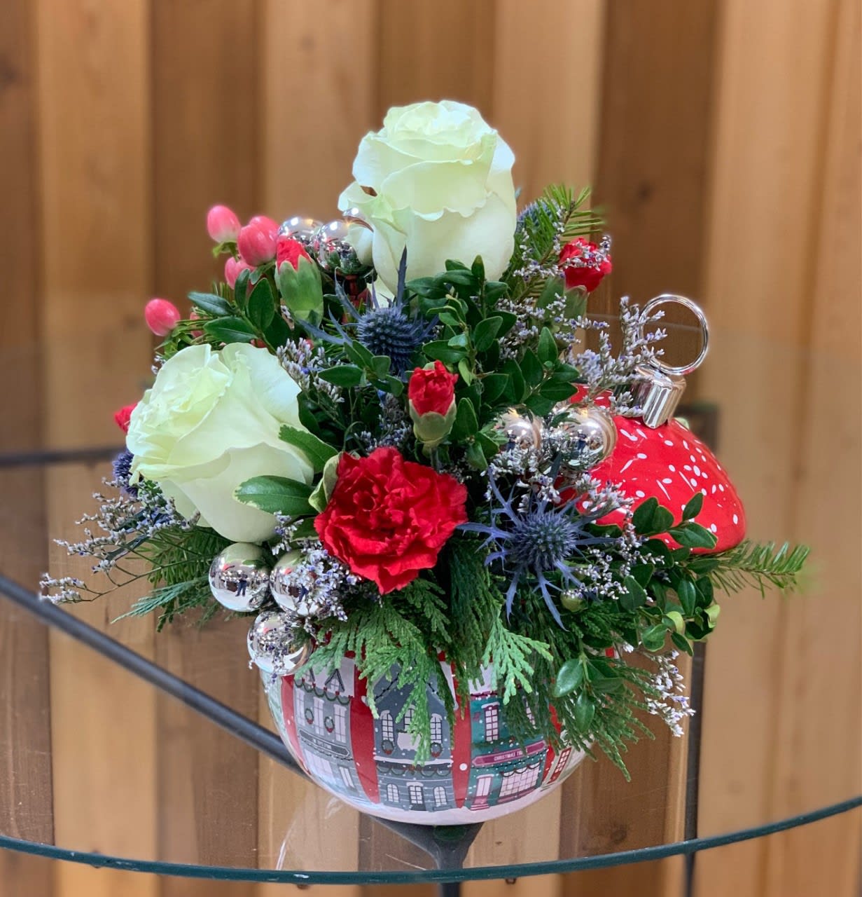 Holiday floral arrangement in a red ornament-shaped container with white roses and red carnations