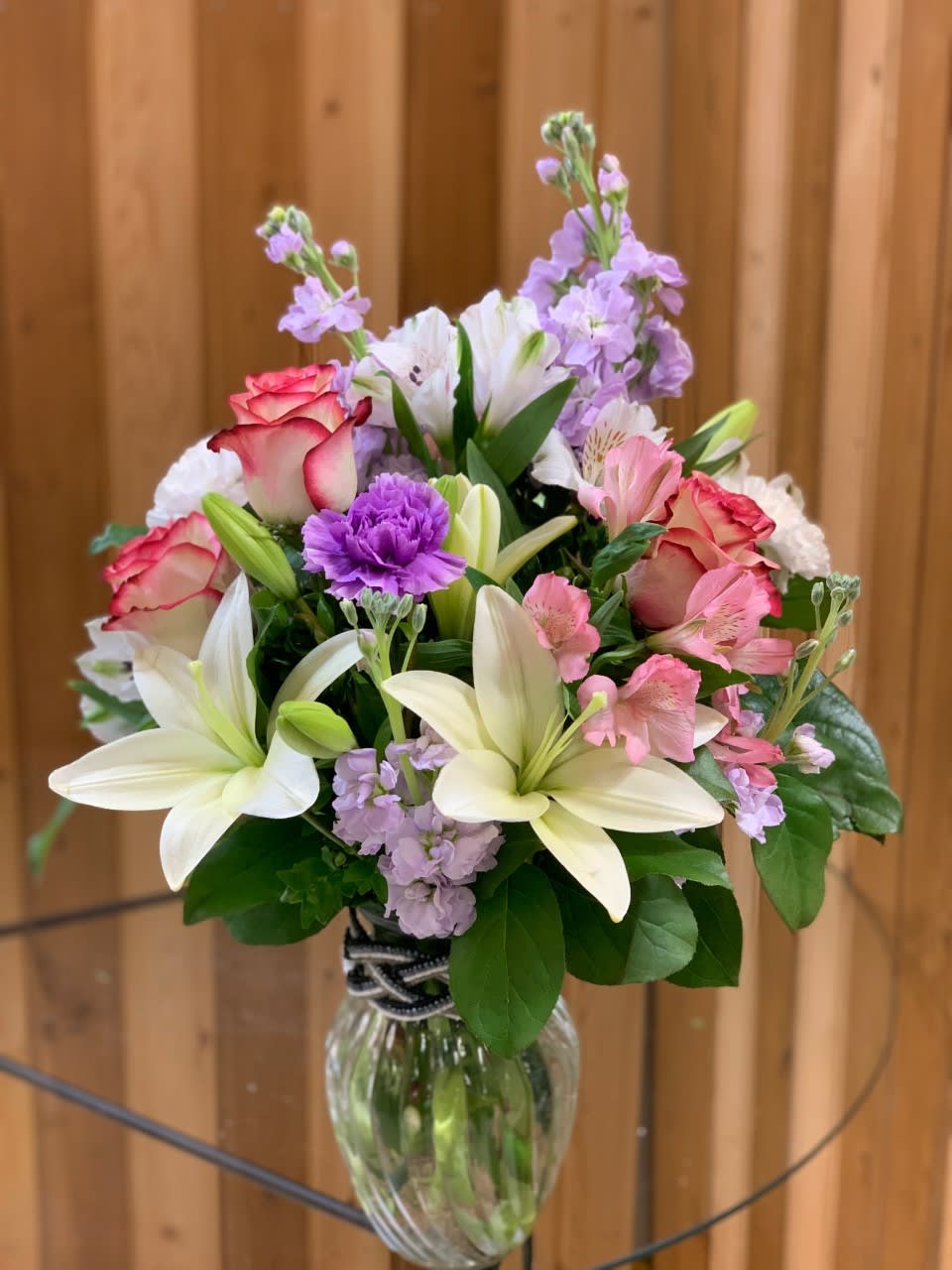 Bouquet of lilies, roses, and purple flowers in a glass vase