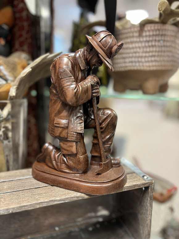 Wooden kneeling firefighter figurine holding an axe